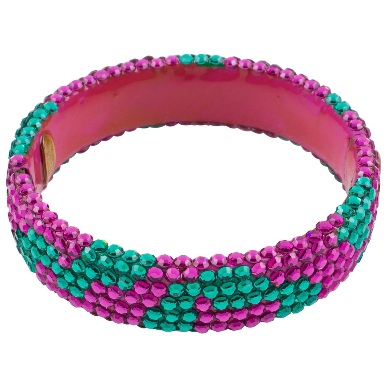 Richard Kerr designed this beautiful statement clamper bracelet in the 1980s. The bangle is made of his signature pave rhinestones and features a large band shape covered with bi-color crystal rhinestones. The piece boasts bright colors of fuchsia