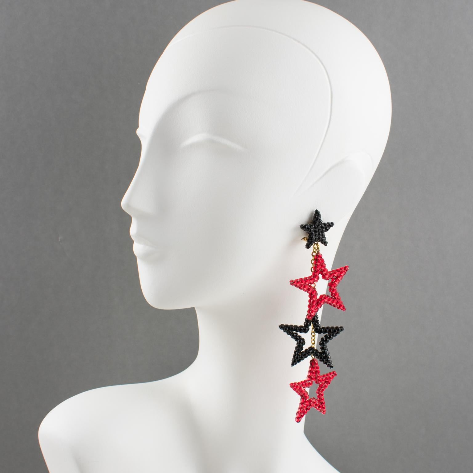 Richard Kerr designed these handsome chandelier clip-on earrings in the 1980s. They bear his signature pave rhinestones. The pieces boast a shoulder-duster shape with three stars-shaped dangling charms, all covered with red and black crystal