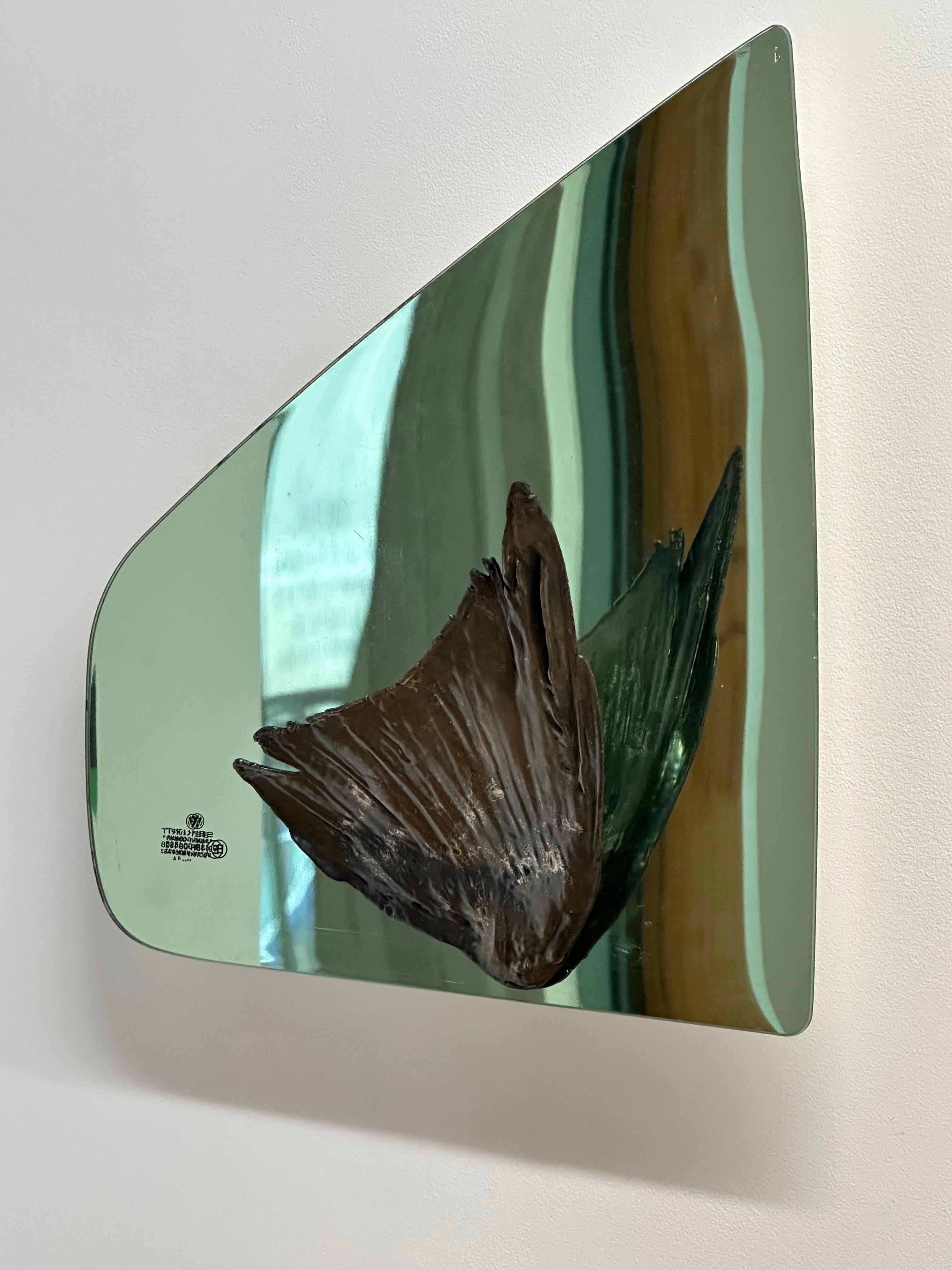 In this wall-mounted sculpture, a copper and nickel-plated crow's wing extends out from a shaped piece of glass, a window from a 1990 Volkswagen Passat mirrored with white gold leaf.

Richard Klein has utilized found objects in his sculptural work