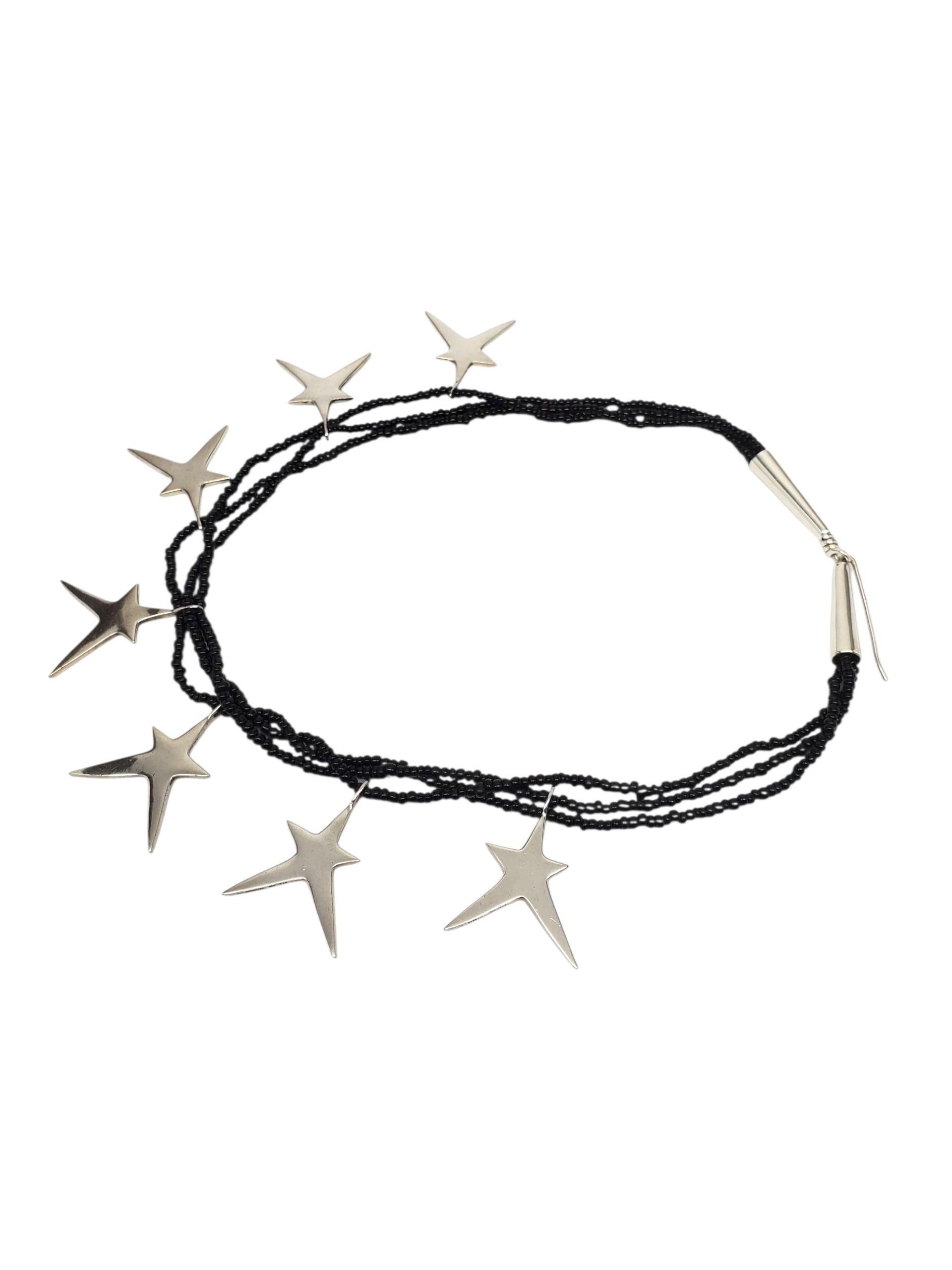 A. Richard Lindsay - Collana con ciondolo con perline a forma di stella in argento sterling.

Questa straordinaria collana con ciondolo in argento 925 fatta a mano da Richard Lindsay presenta 7 stelle allungate sospese da tre fili di perline nere