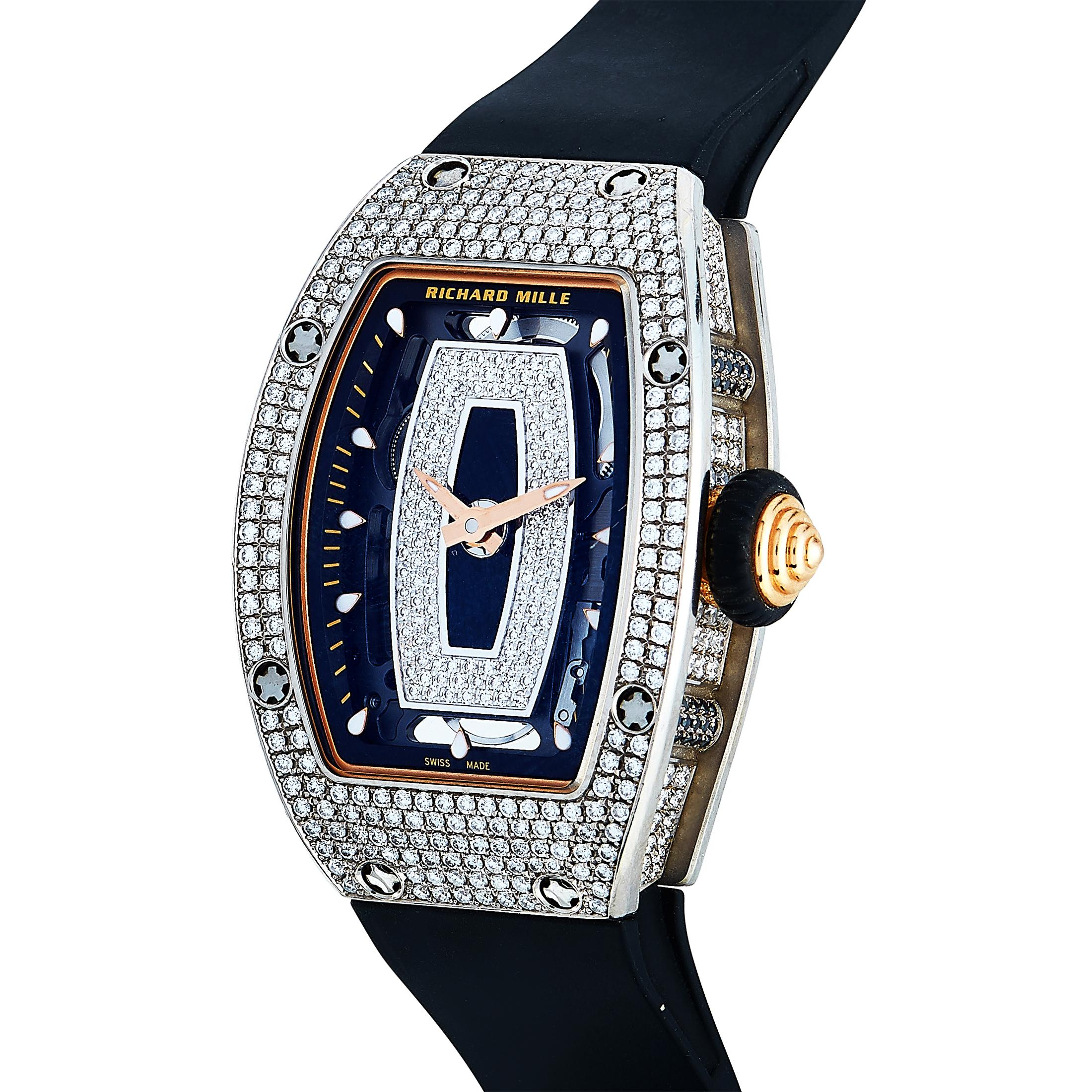 This is the Richard Mille Automatic watch, reference number RM 07-01 RG.

It is presented with a diamond-embellished 18K white gold case that boasts see-through back. The case is water-resistant to 50 meters and worn on a black rubber strap, secured