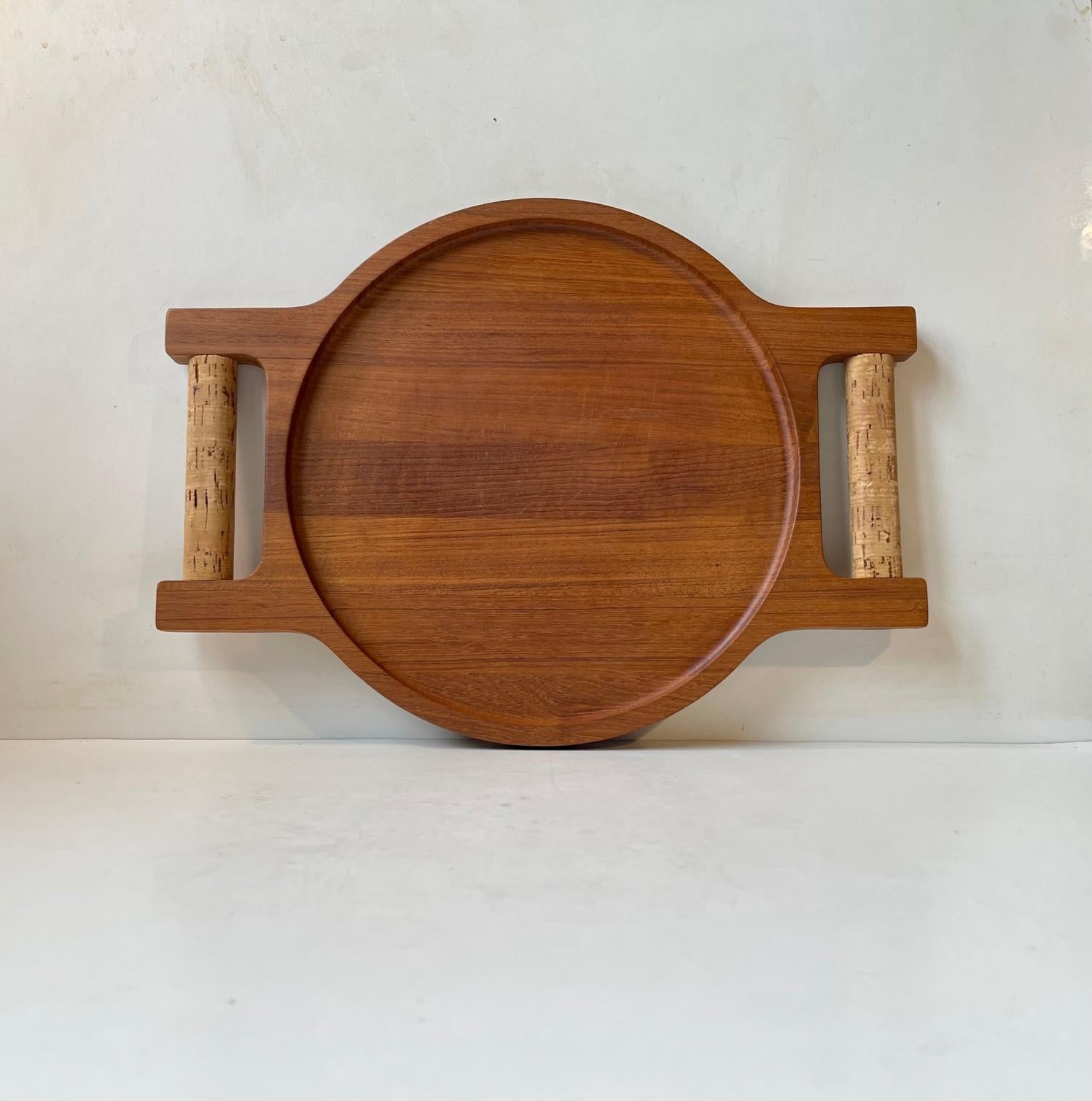 A rare double sided tray with serving tray to one side and cutting board to the other. Its made from solid teak partially stacked to display the wooden grains and its assembled without the use of any metal. It features stylish solid cork handles.