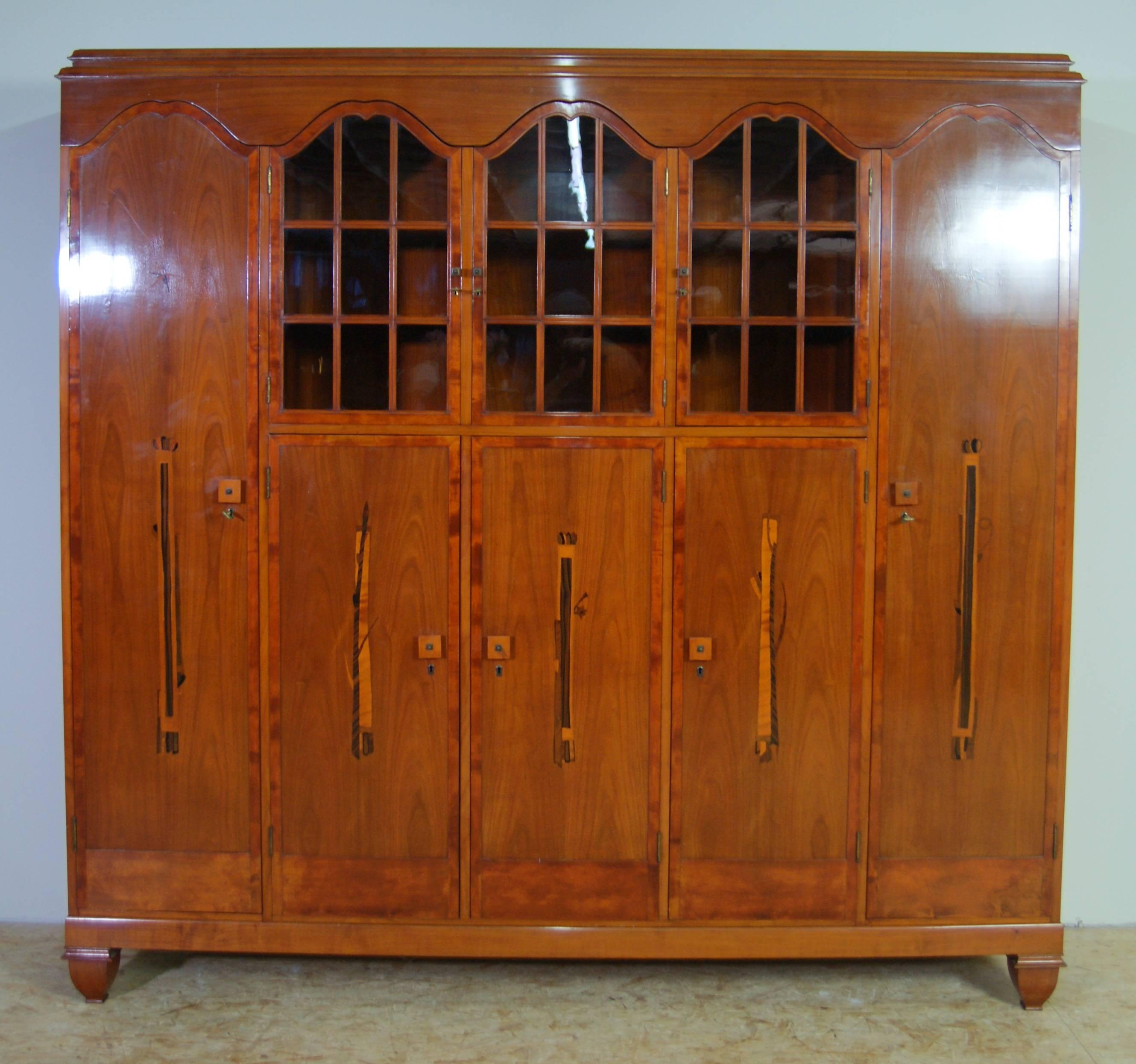A dining room set from the Art Nouveau era by Richard Riemerschmid. It consists of a great display case, sideboard, commode, mirror and a table with six chairs of which all parts can be seen above. Every part is held in a brown-red birch veneer,