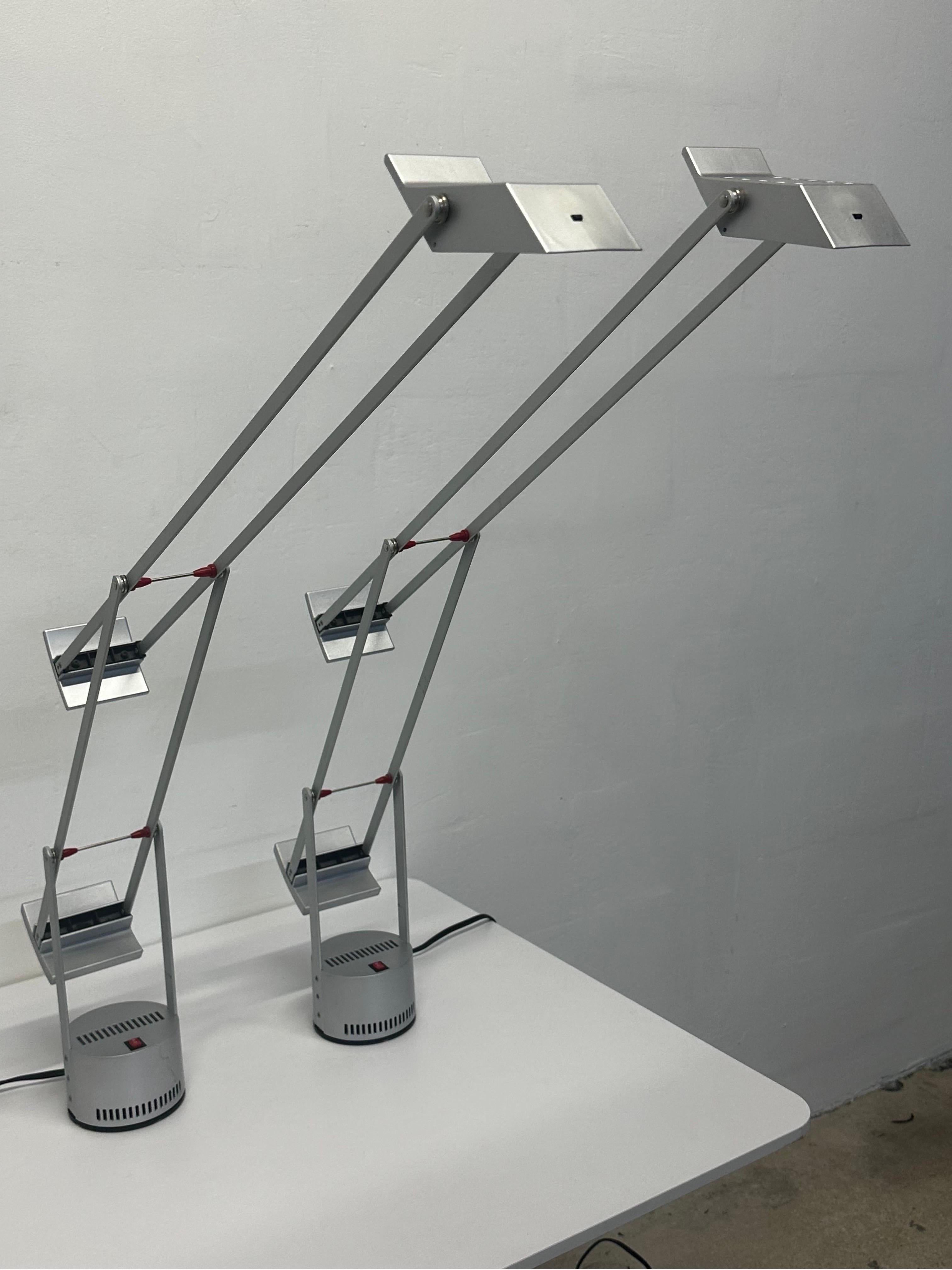 Pair of rare, signed Tizio table or desk lamps from first production run of silver and red color scheme.  Only 3000 lamps were produced and each lamp is numbered (551 and 1043).  Fully adjustable and lamps have high/low toggle for desired brightness.