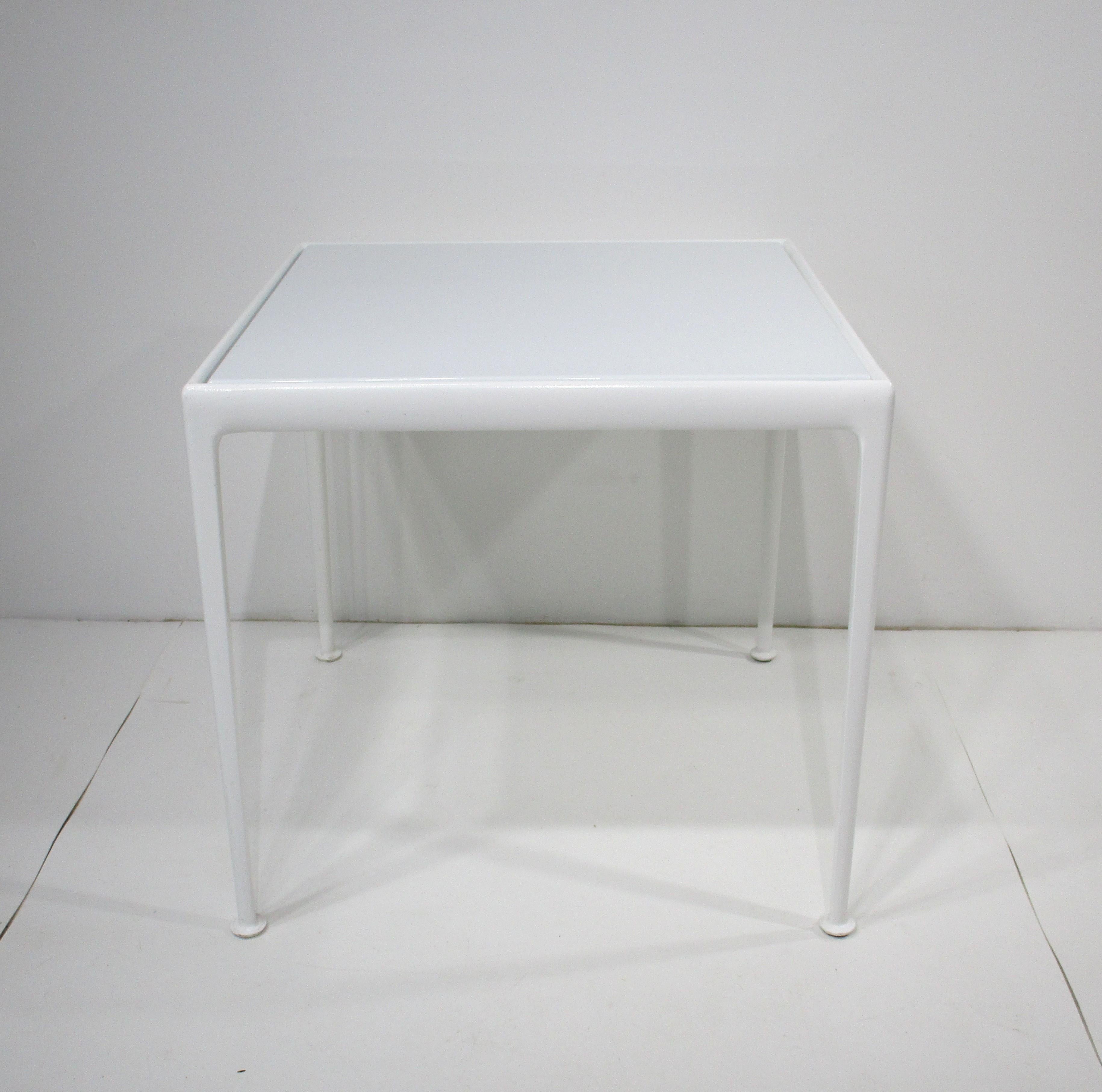 A great Mid Century outdoor or indoor smaller dining or game table from the Leisure Collection manufactured by Knoll . Having a bright white enameled metal top sitting on a cast white painted aluminum base with pad styled feet  . Designed by Richard