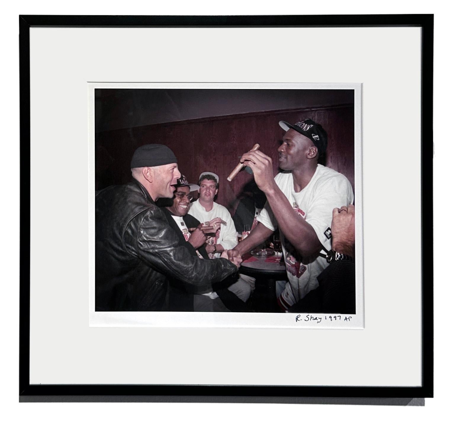 Cigars come out and congratulations abound as Michael Jordan wins his 5th Championship in 1997.  Here, Richard Shay has captured the moment when fan Bruce Willis looks at the superstar with such admiration and awe to be in his presence.  This A.P.