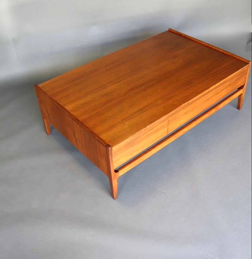 Richard Thompson designed this sleek coffee table for Glenn of California. It is constructed in beautiful walnut with a solid oak drawer. Book-matched grain across the front of the drawer has a unique feature, the drawer pushes through on either