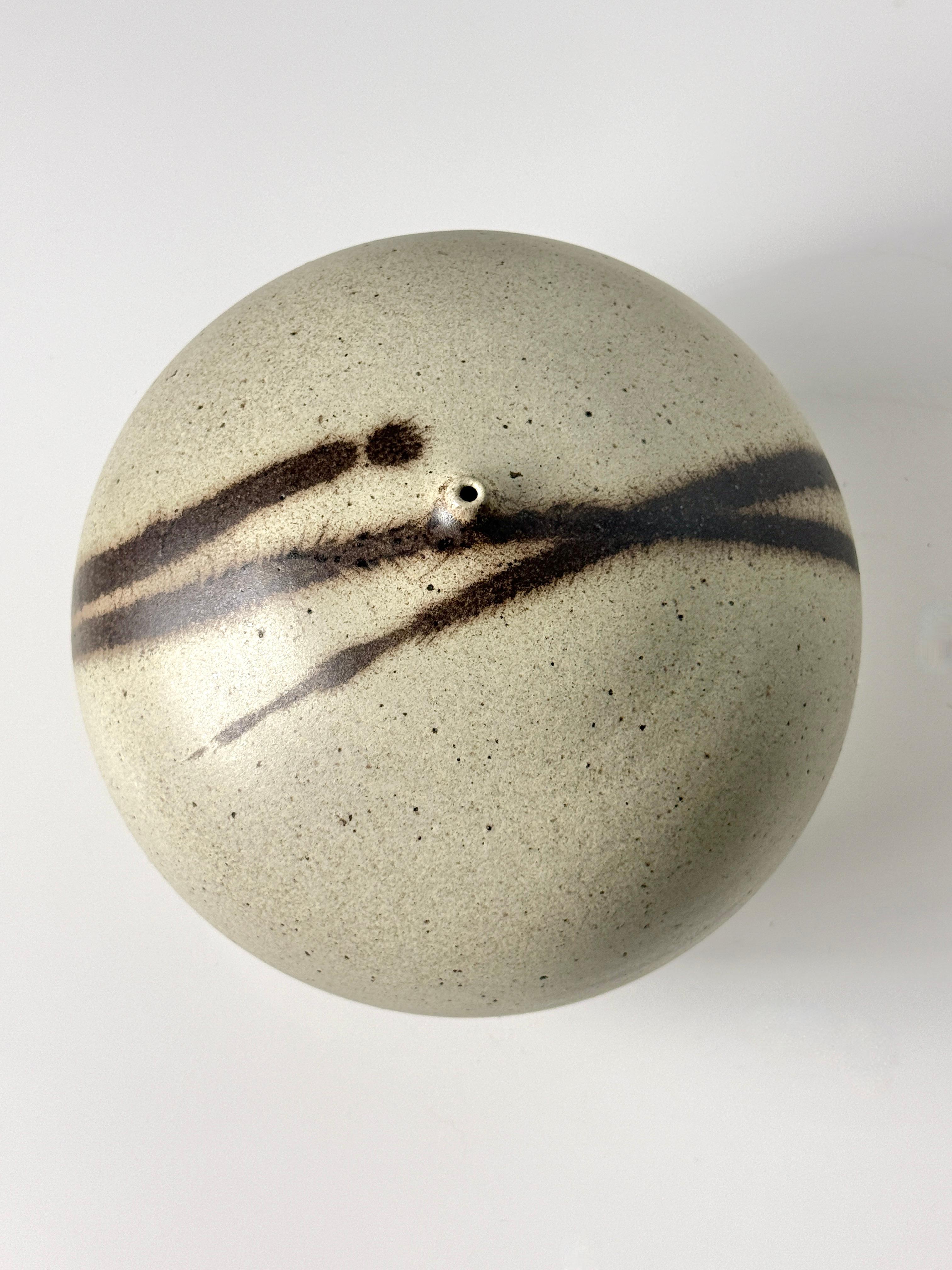 Large studio ceramic vessel by Virginia artist Richard Tuck circa 1970s

Rounded form in earthy speckled beige glaze with deep brown gestural brushstrokes and a small centered opening

8 inch diameter
8 inch height

Richard Tuck (1948–2013) 
Born in