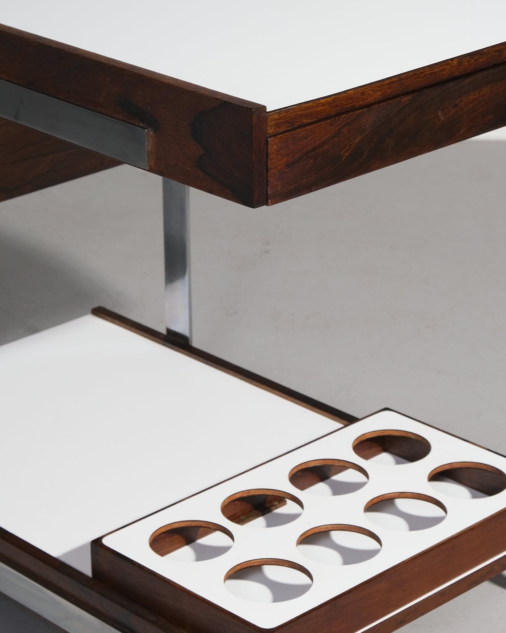 Richard Young for Merrow Associates Bar Cart, 1965 – Rio Rosewood & Chrome

A bar cart / drinks trolley designed by Richard Young for Merrow Associates in 1965, featuring a chrome-plated steel frame and two tiers of Rio rosewood shelving. The wood’s