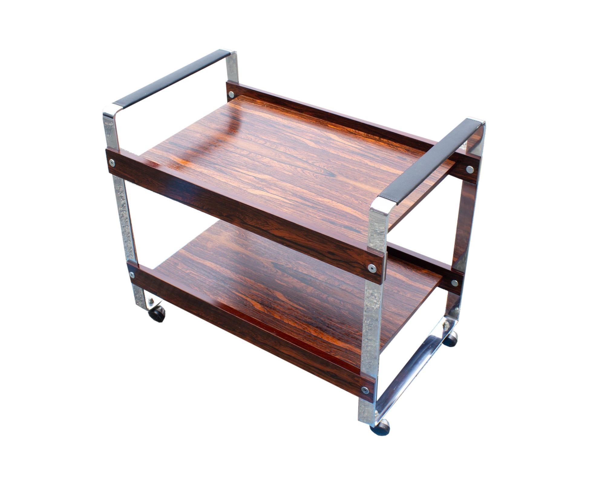 A bar or tea cart designed by the British designer Richard Young. The cart has chrome sides with black faux leather wrapped around the top and two shelves with a rosewood veneer. The car stands on four casters and is unmarked.

