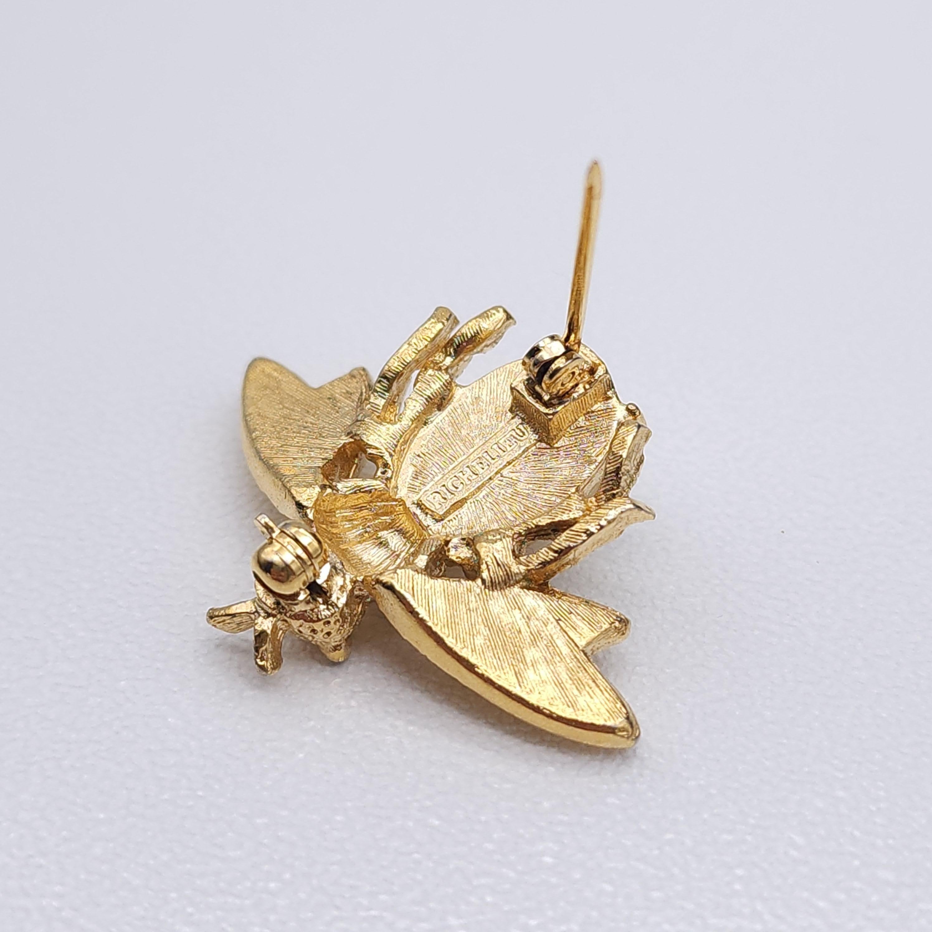 Giocosa ed elegante, questa spilla vintage Richelieu trasforma l'umile ape in un accessorio chic dal fascino senza tempo.

Realizzata in metallo dorato, questa spilla ape dai dettagli meravigliosi presenta un cabochon di perla finta luminosa come