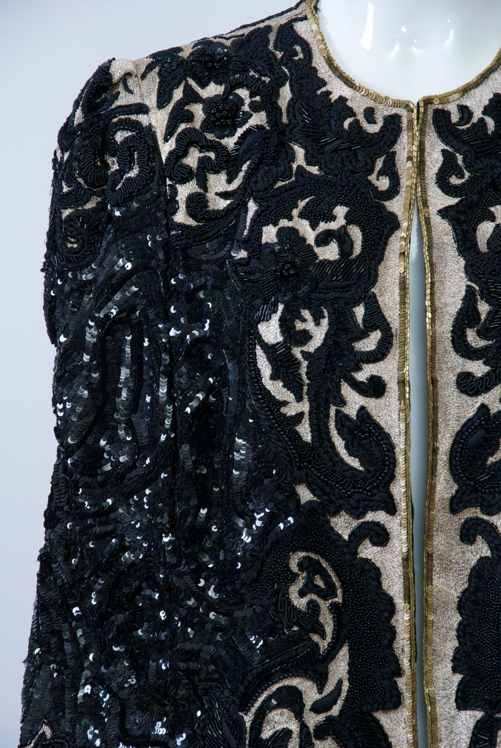 Extravagant verzierte Abendjacke von Richilene, um 1980, mit Stickereien, Soutache und Perlen auf komplementären Grundstoffen, entweder einfarbig schwarz oder mit Goldfäden, die auf der Vorderseite und an den Ärmeln hervorgehoben sind. Eine schmale