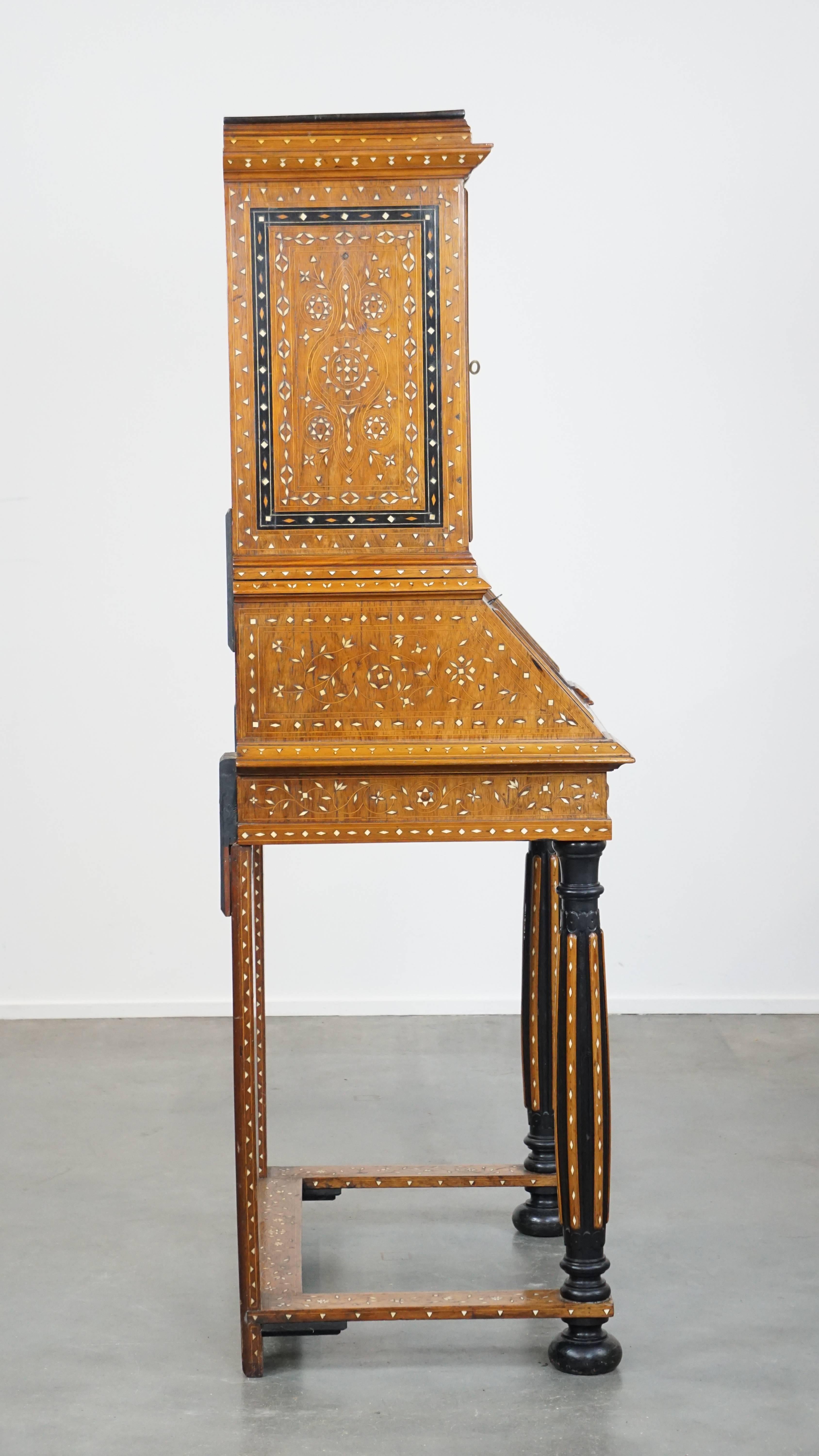 This highly decorative, museum-quality antique Italian secretary is beautifully adorned with intricate inlays featuring striking and decorative motifs. The piece has two doors with a shelf behind them, while the lower section functions as a