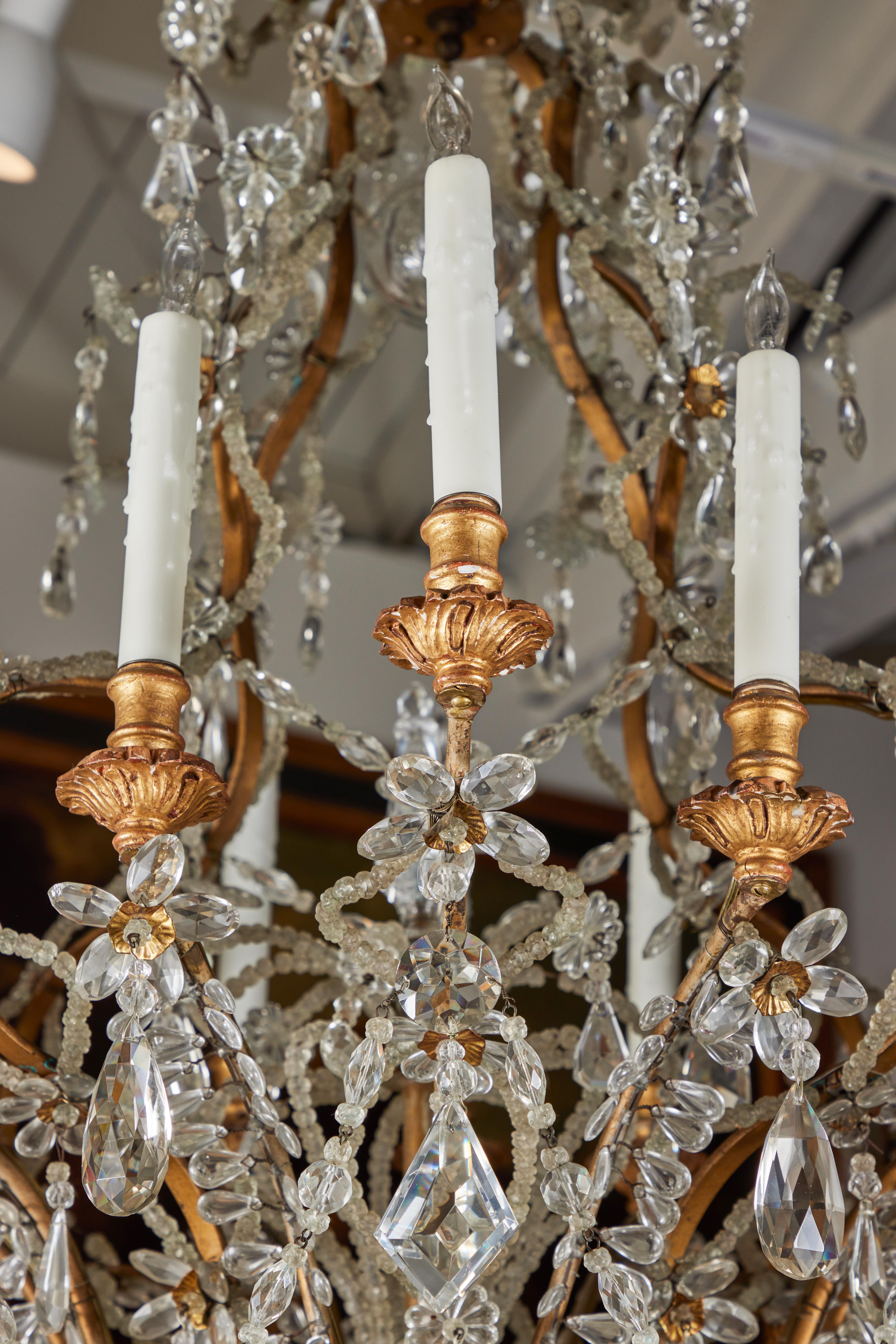 A c. 1875, Italian chandelier with a striking, serpentine carriage rising to 12, elongated arms with giltwood, foliate form bobesh. The entire piece encrusted with crystal in a variety of shapes, including pearl-strings, faceted diamond and oval