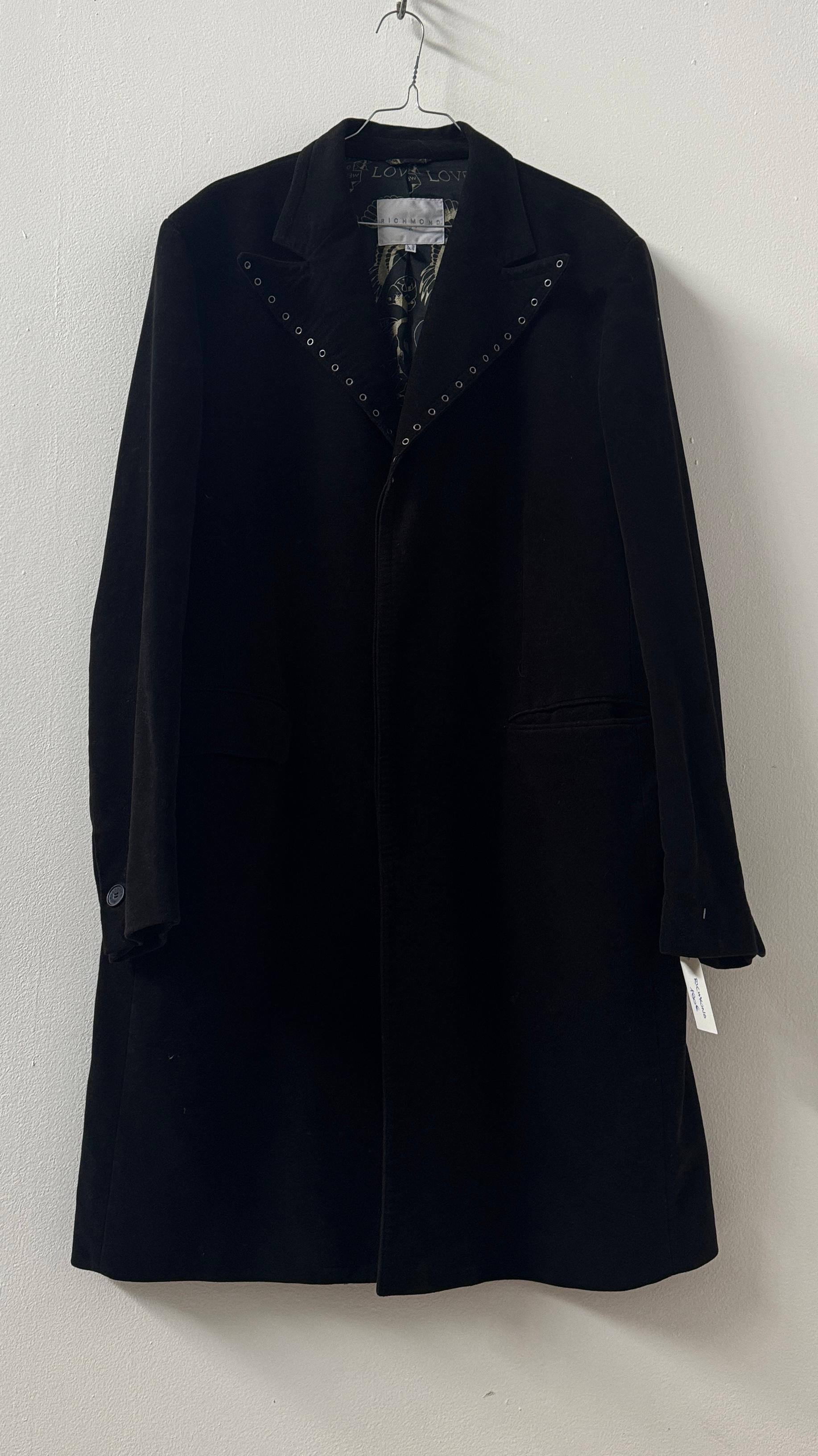 Este abrigo de Richmond X es un ejemplo perfecto del estilo atrevido y poco convencional que ha convertido a la marca en un icono. Confeccionado en suave terciopelo de algodón negro, presenta una silueta estructurada y ligeramente entallada,