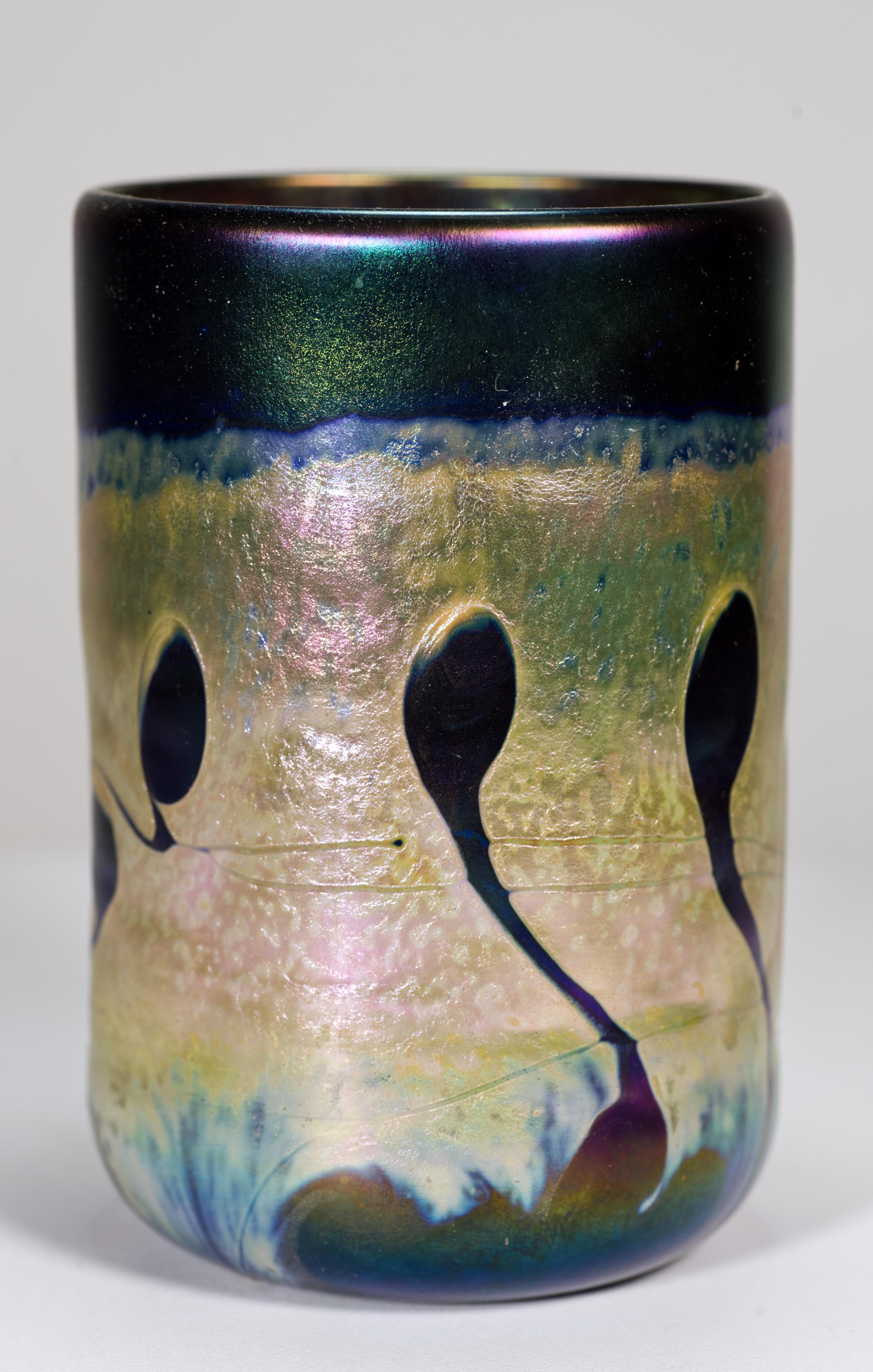 Il vaso di gemme in vetro artistico vintage presenta decorazioni in vetro fuso multicolore con finitura iridescente. Un forte motivo grafico astratto scorre lungo le linee del vaso cilindrico di forma minimale, mentre elementi in vetro fuso
