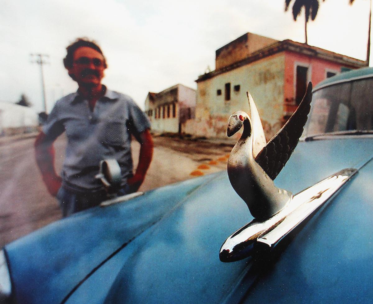 Photographie illustrant la vie quotidienne à La Havane, à Cuba, par le célèbre photojournaliste Rick Hunter. Cette œuvre présente un gros plan d'un ornement de capot de voiture classique en forme d'oiseau. Signé par l'artiste dans le coin inférieur