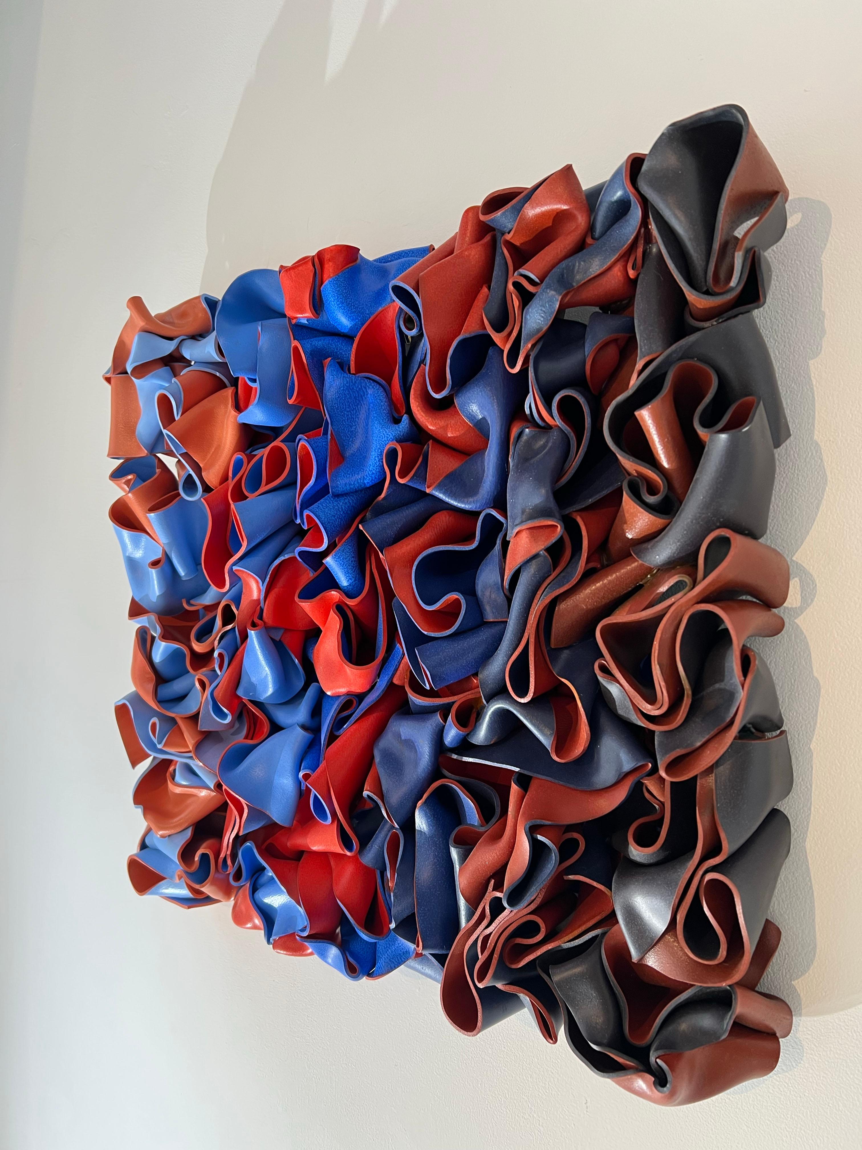 An abstract sculpture hand molded with styrene. This piece is very consist of many shades of orange and blue, contrasting against each other. 

Rick Lazes is a three dimensional artist who works in a variety of media including wood, plaster,