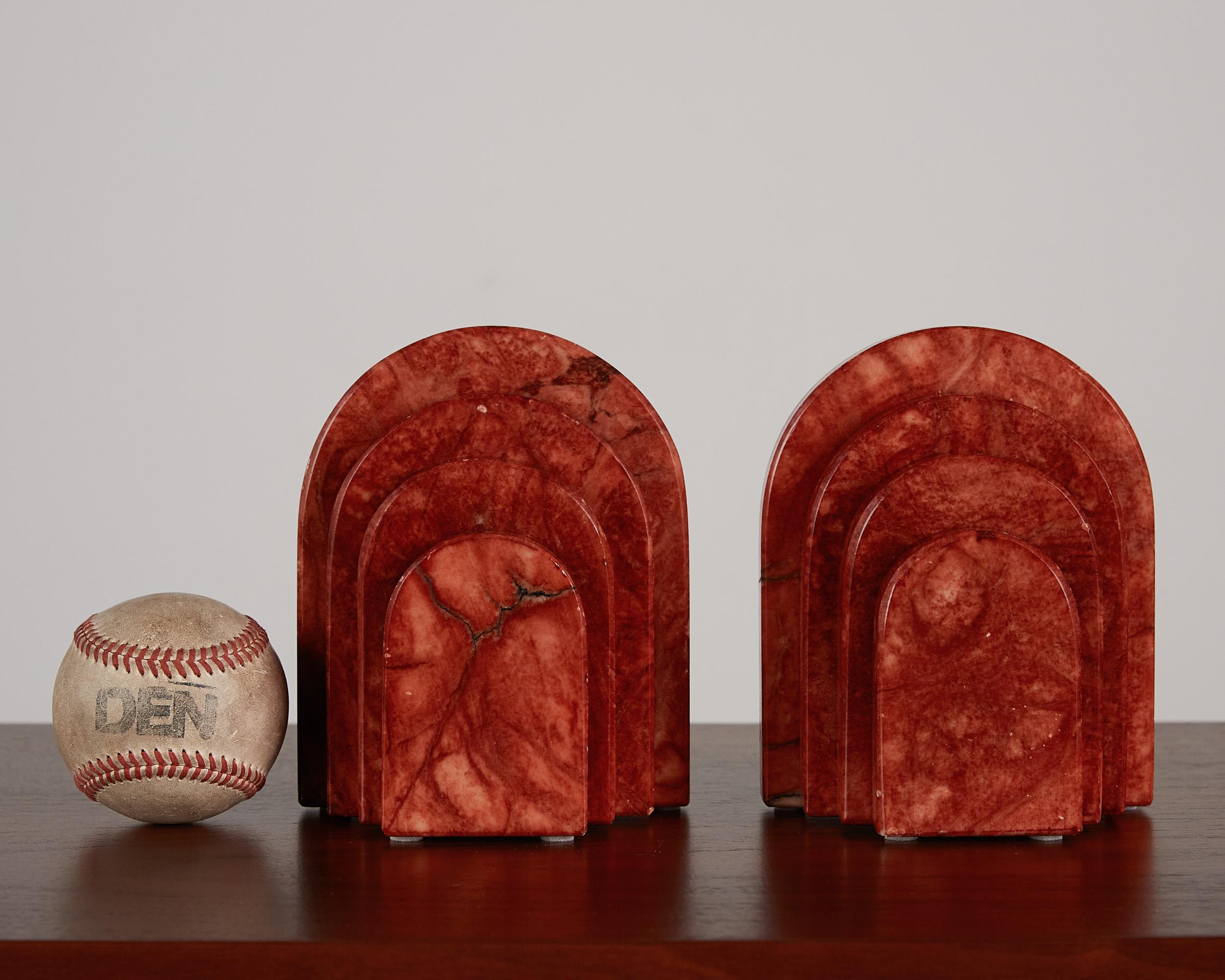 These postmodern bookends, by Rico Industries, Italy, c.1980s. These Red Alabaster bookends features a curved tiered cascading design. The deep red and black veining is highlighted against the cream accents of white throughout the stone. They would