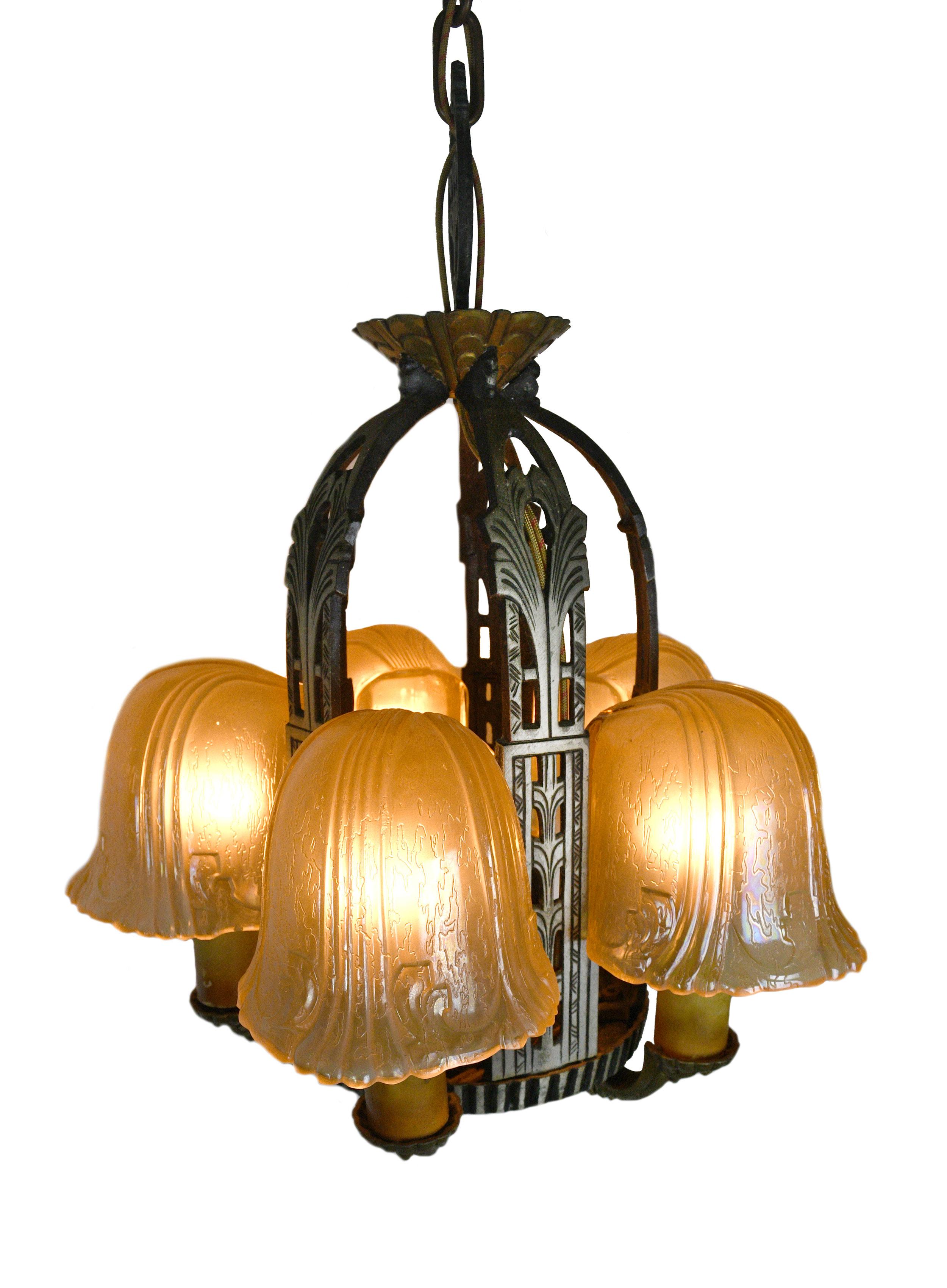 This “Riddle” 5 candle slip shade chandelier features a classic art deco design and finely crafted geometric detailing. A pleasing mix of sharp angles and curves run throughout this stunning aluminum chandelier. 

The famous Edward N. Riddle