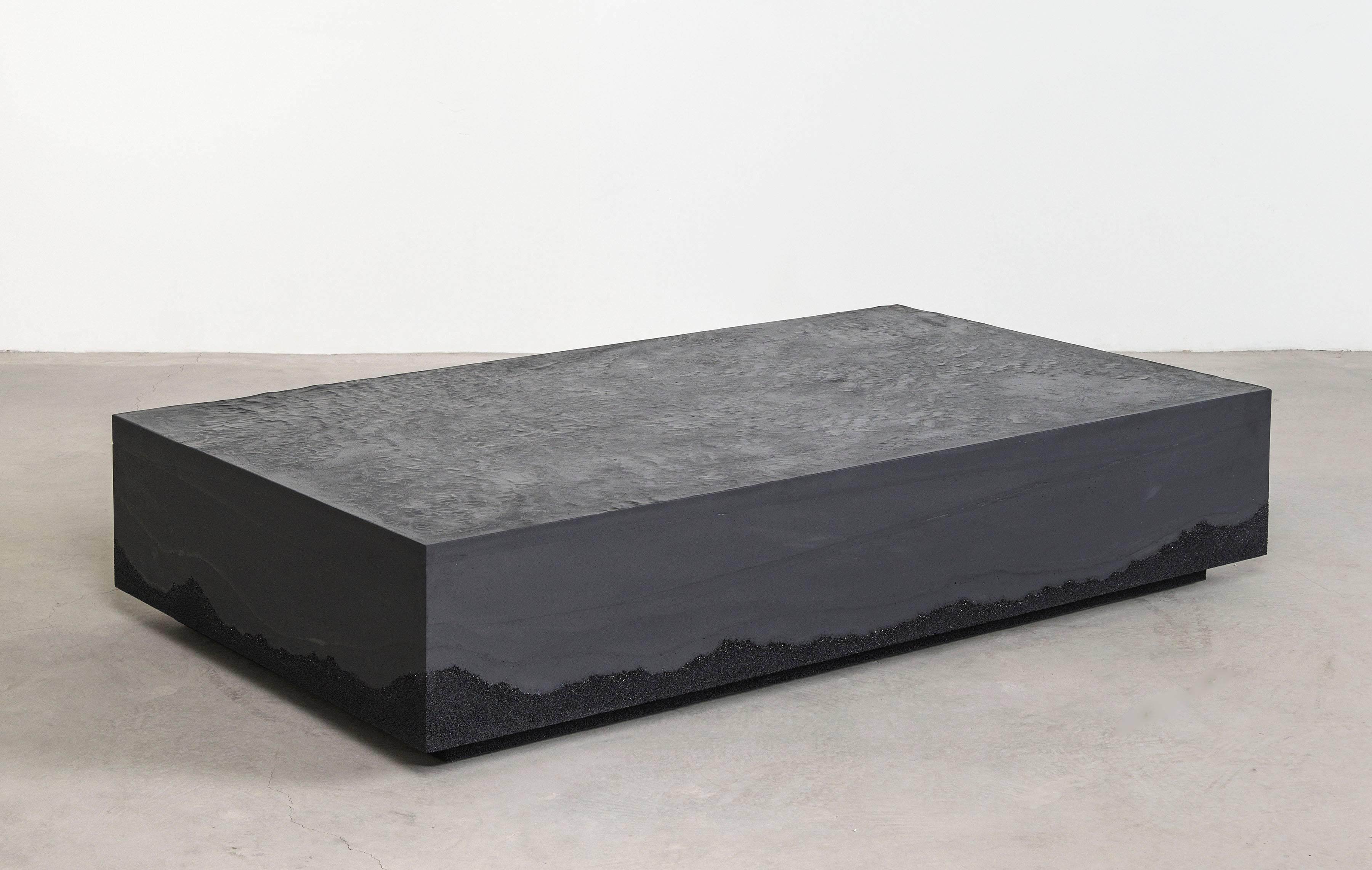 Composed in a language of landscape-oriented abstraction, the made-to-order coffee table is cast from hand-dyed cement and silica. Poured by hand over the black granules, the black cement merges the materials to create an effect evocative of a