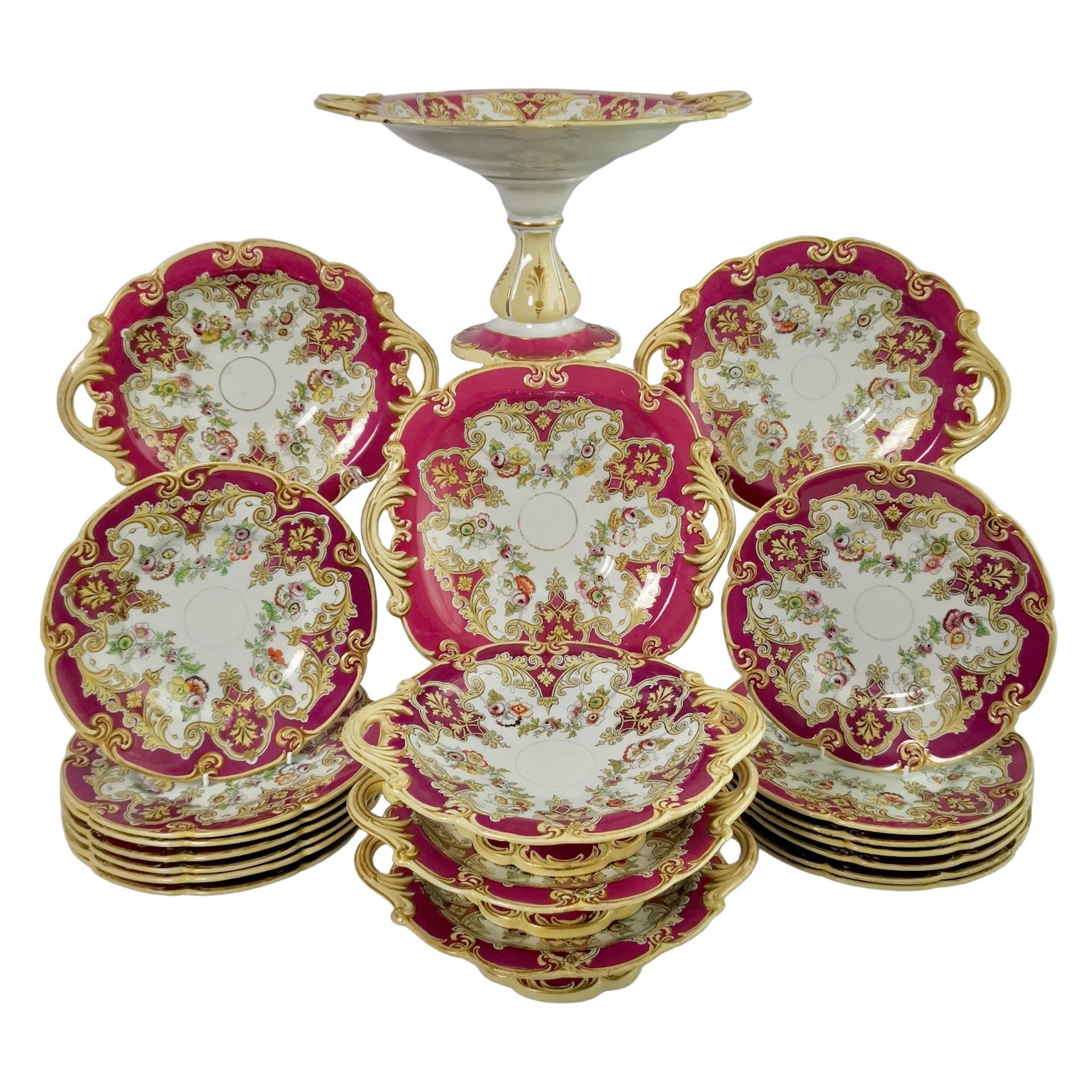 This is a fabulous large dessert plate made by E.J. Ridgway around 1870. The service has a dark fuchsia pink ground and printed and hand coloured flower festoons. The service consists of a high tazza, three round low comports, two oval low comports,