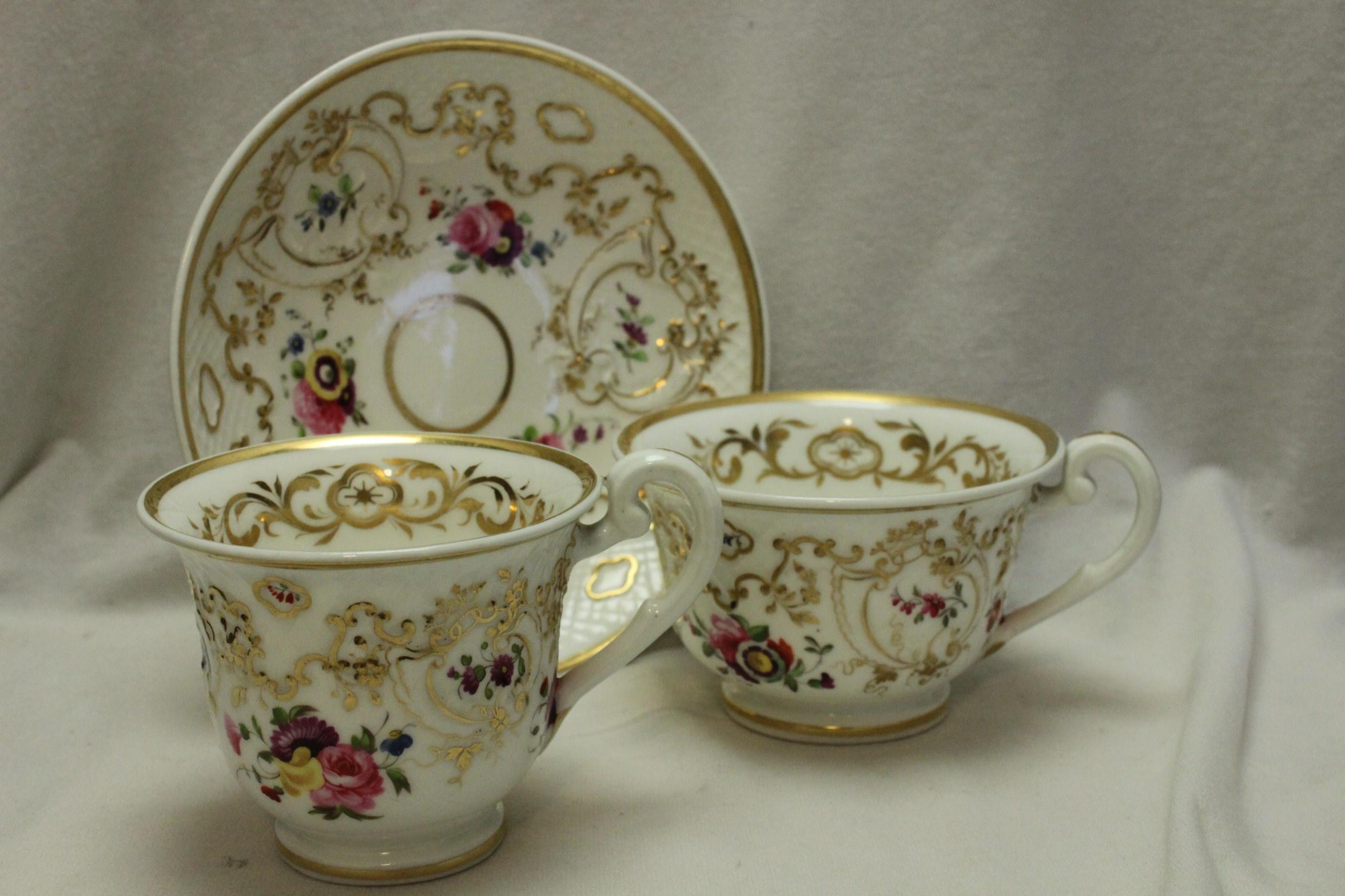 This delightful Ridgway hand painted and gilded porcelain trio is decorated with Ridgway's pattern 2/824 on their Round Embossed shape and comprises a tea cup, a coffee cup and a shared saucer. The gilding has been very delicately done and enhances