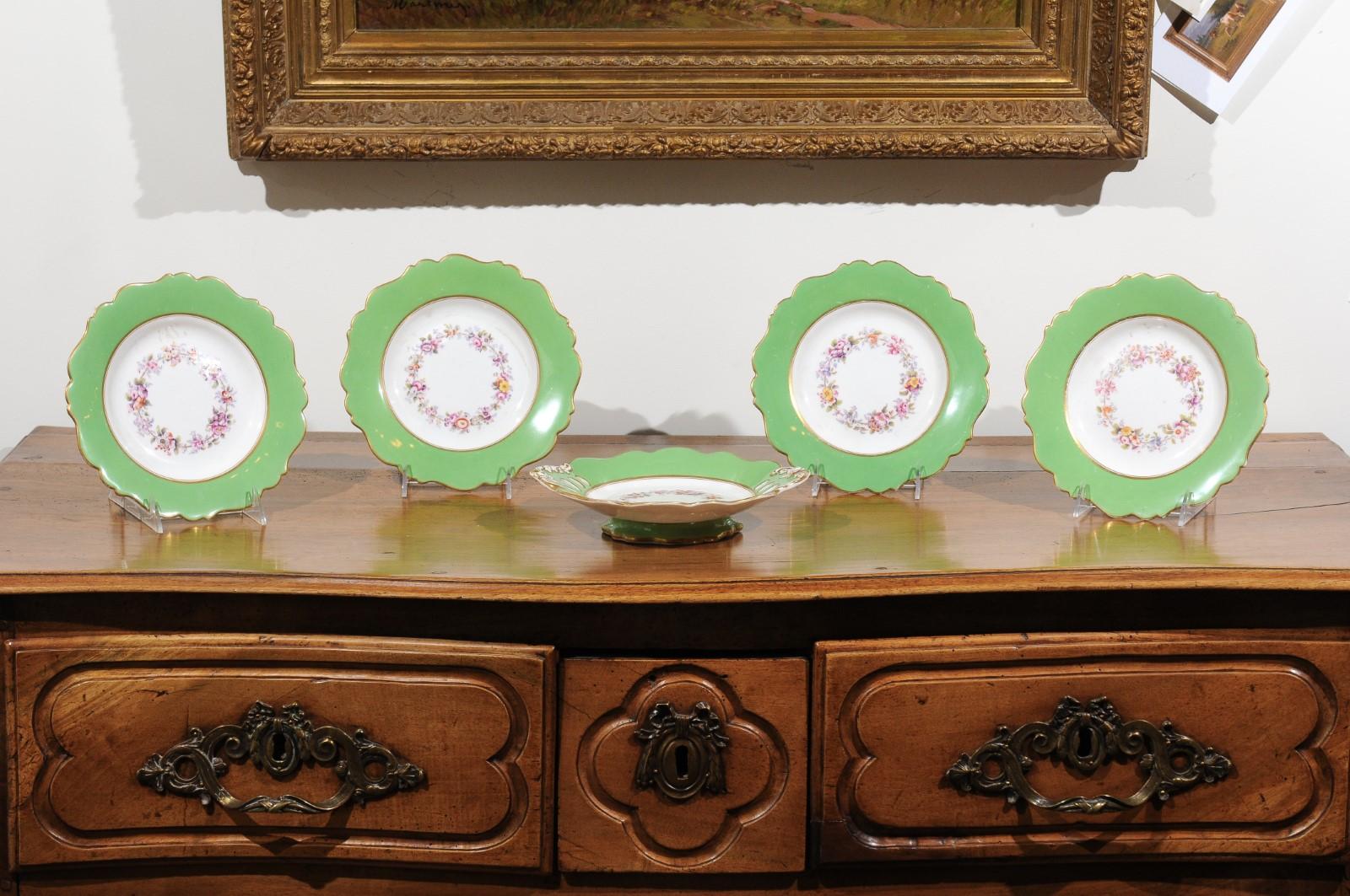 Four Ridgway porcelain hand painted dinner plates and one compote from the 19th century, with green rim and floral decor, priced and sold separately. Born in England during the 19th century, each of these Ridgway porcelain pieces features a lovely