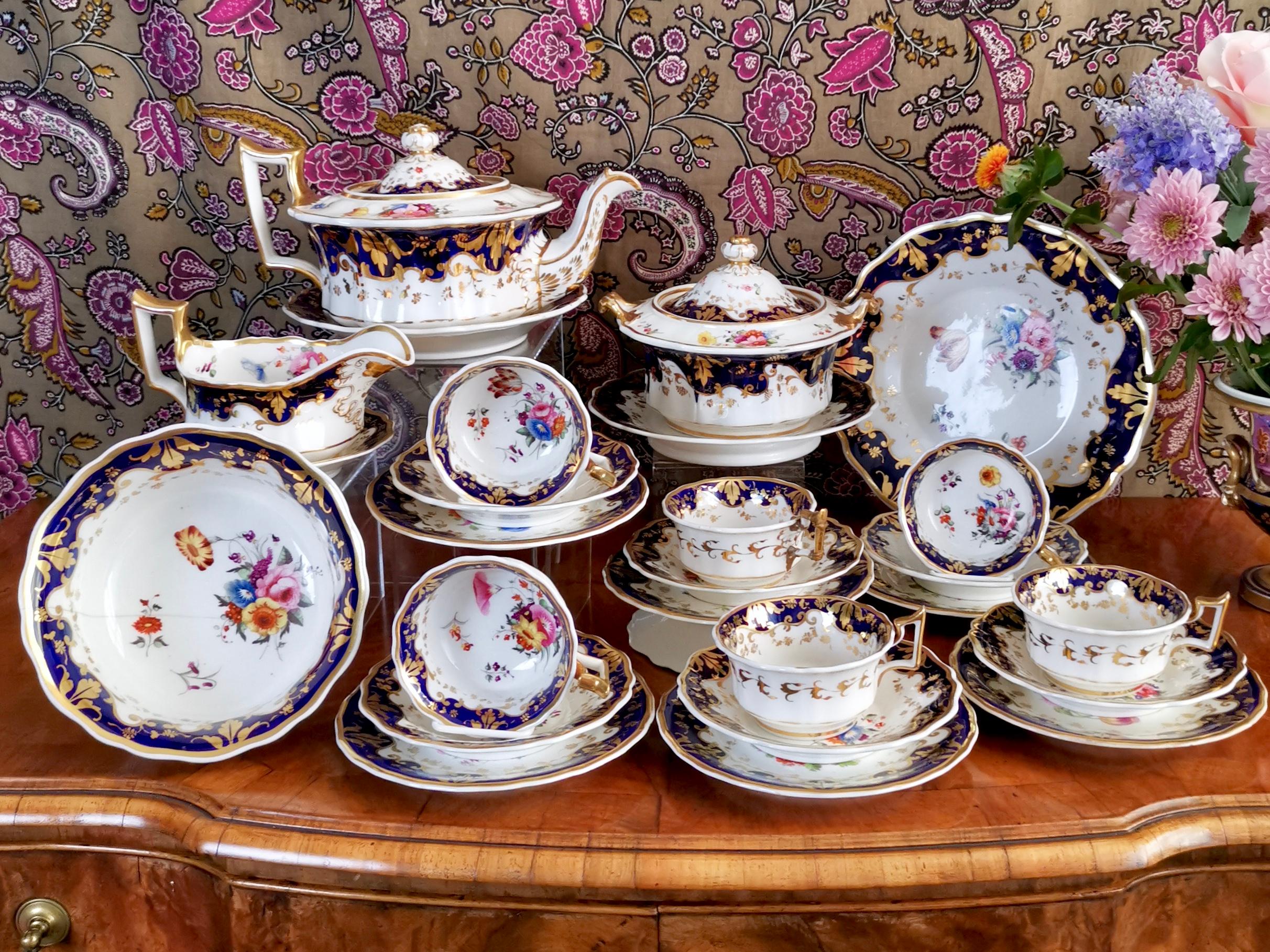 This is a stunning Ridgway porcelain tea service made between 1820 and 1825, which is known as the Regency period. It is decorated with a cobalt blue ground, beautiful hand painted flowers and gilt. The service consists of a teapot and stand, a