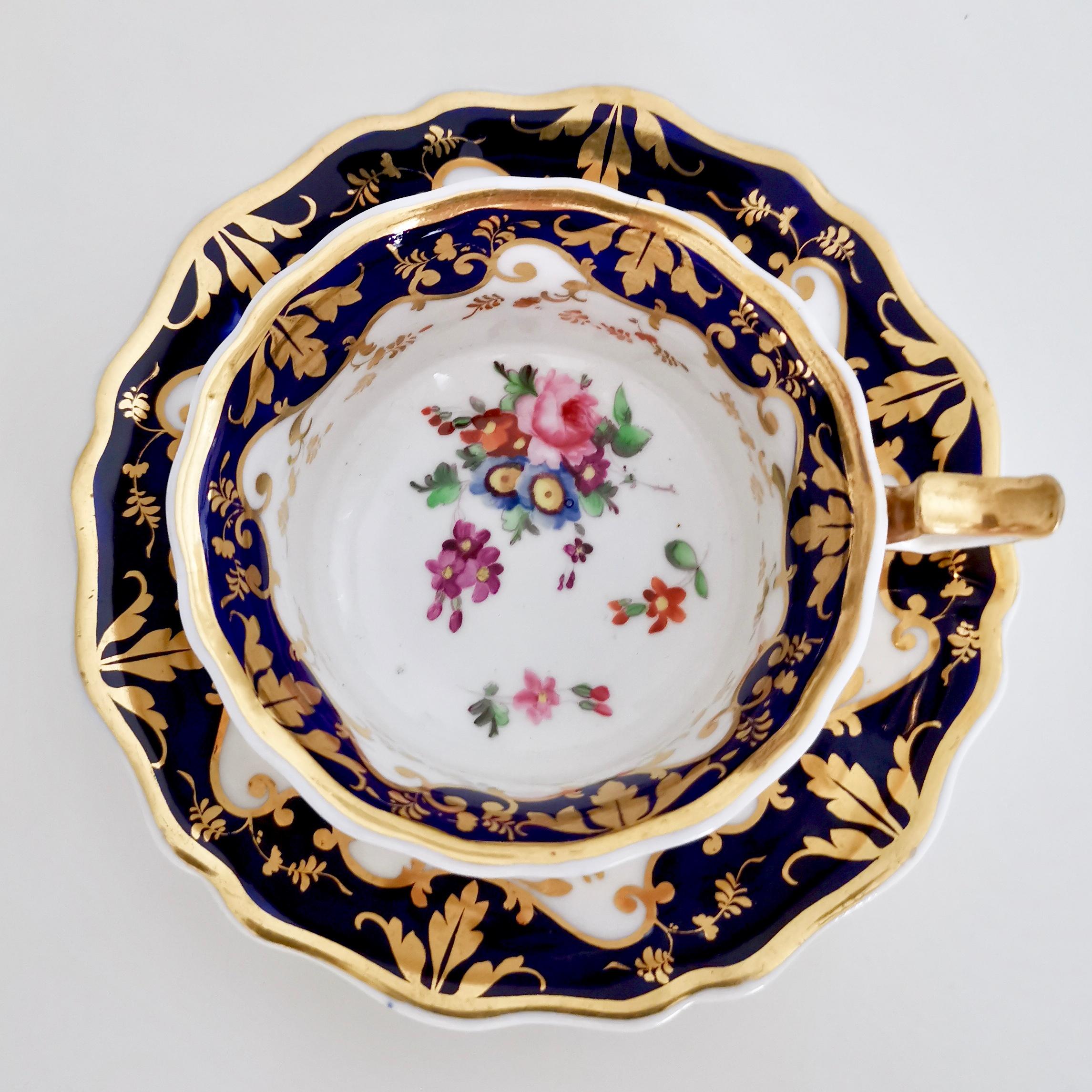 This is a Ridgway teacup and saucer made between 1820 and 1825, which is known as the Regency period. The set has a cobalt blue rim and beautiful hand painted flowers. The shape is typical for its time and is called the 