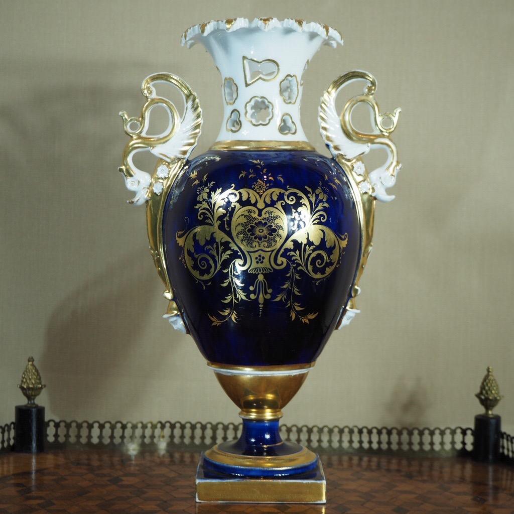 Unusual ridgway vase, with acanthus leaf rim above a deep blue body, the handles formed as dragons above a spear and trident reaching below to a Roman soldier head, the body finely gilt with foliate scrolls. 

Circa 1835.
