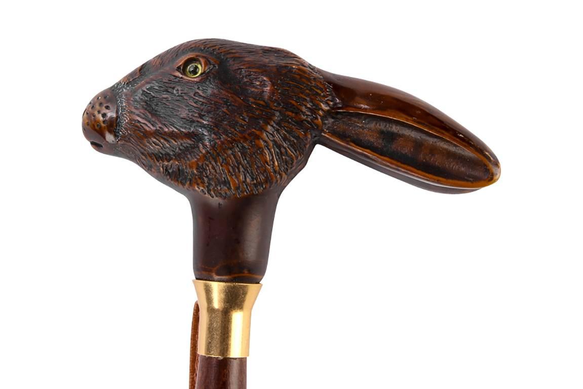 Riding crop with a carved rabbit head finial, walnut, carved rabbit head with inlaid eyes, brass collar and a ribbed tie, leather hoop strap attached to side at top.

Condition: Expected wear and signs of use including some light surface