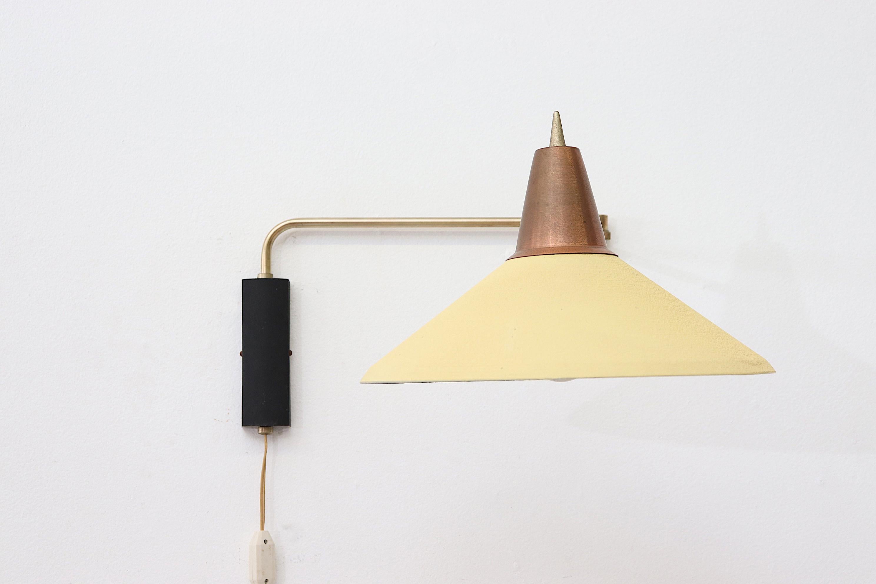 Yellow and copper Rietveld style industrial wall mount lamp with an articulating arm and black metal wall mount. In original condition with visible wear and patina consistent with its age and usage, another one is available with black shade
