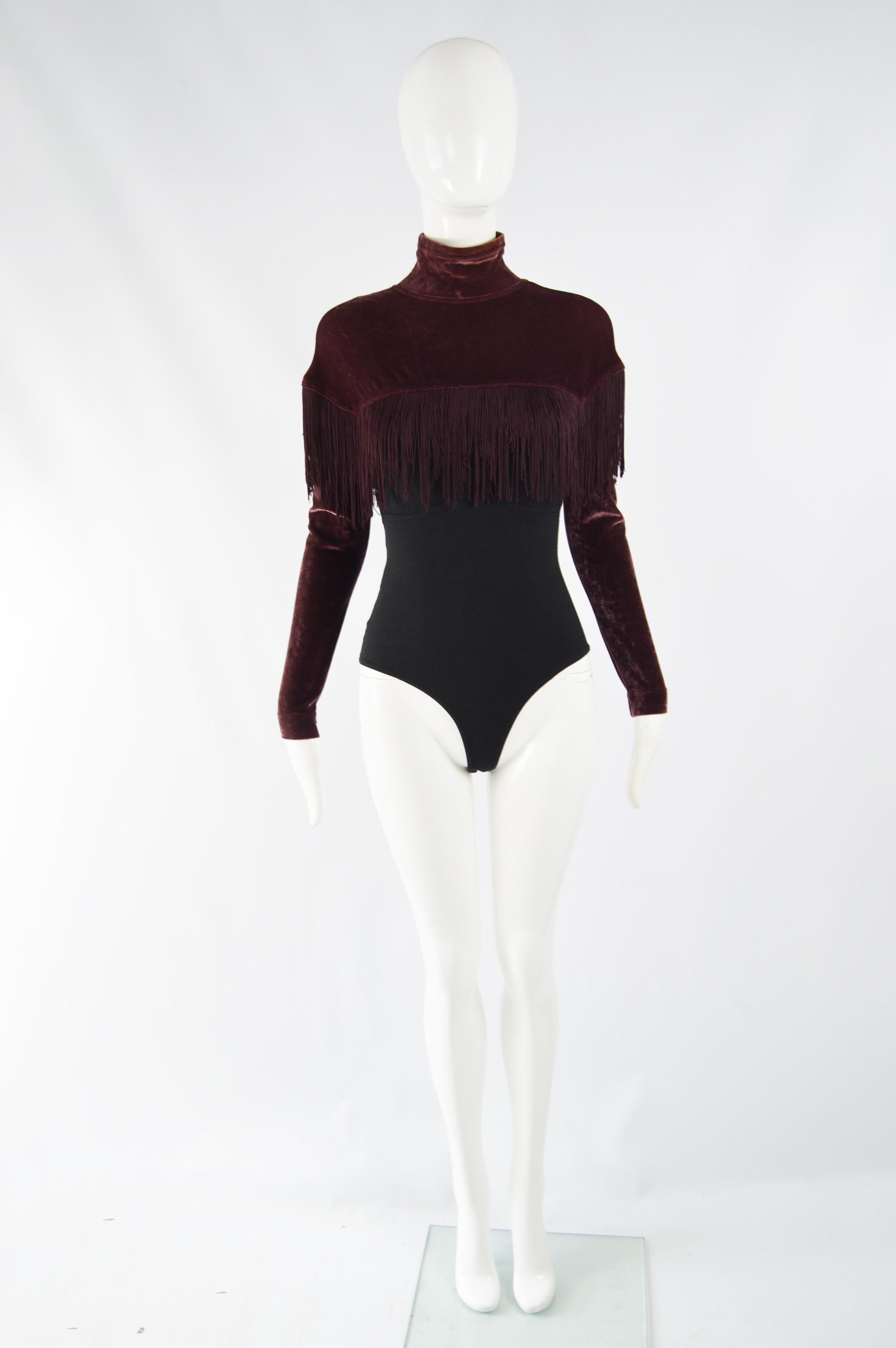 A fabulous vintage body suit from the 90s by luxury fashion designer, Rifat Ozbek. In a wine colored velvet on the long sleeves and high neck with fringe adding a playful touch and a black knit body.

Size: Unlabelled; fits like a modern womens UK