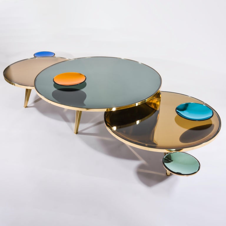 The Riflesso table is designed around a tinted and mirrored double lens glass top which gives the piece a unique sense of depth. Can be upgraded with two decorative mirrored glass dishes; One that can be mounted on a removable lateral bracket and