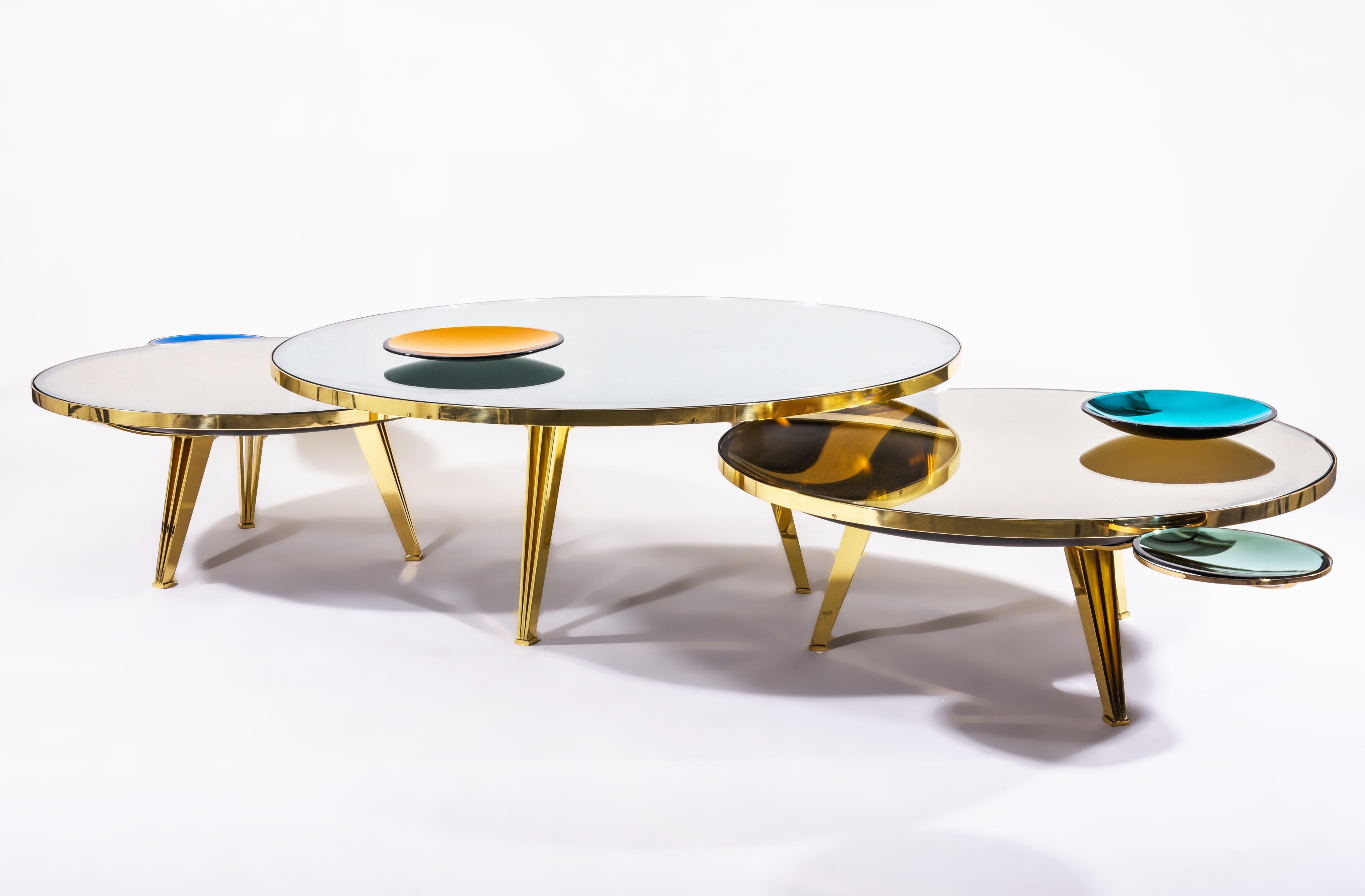 The Riflesso table is designed around a tinted and mirrored double lens glass top which gives the piece a unique sense of depth. Can be upgraded with decorative mirrored glass dishes; One that can be mounted on a removable lateral bracket and the