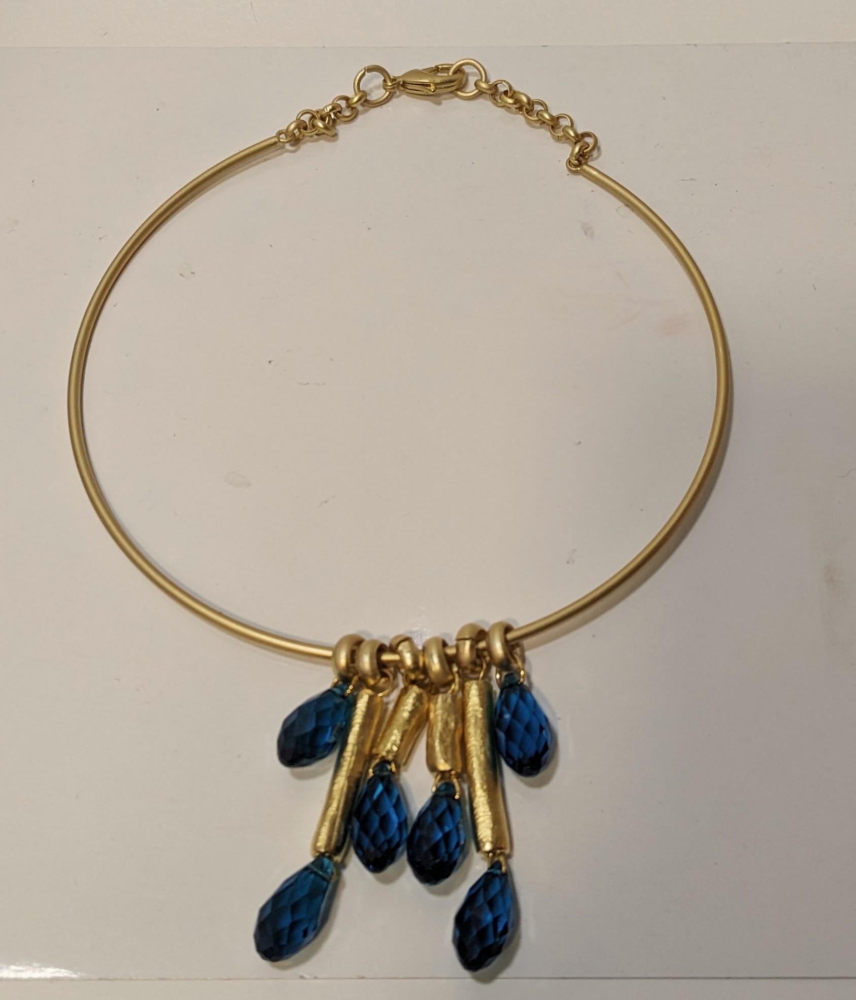 Rigid Choker with Tubes and  Capri Blue Crystals
All in 18 Karat Matte Gold Plating. It has a Carabiner Closure.
The crystals can also be emerald green.
Neck measurement  42cm (16,53 inches)


Pradera Fashion Division  is specialized in European