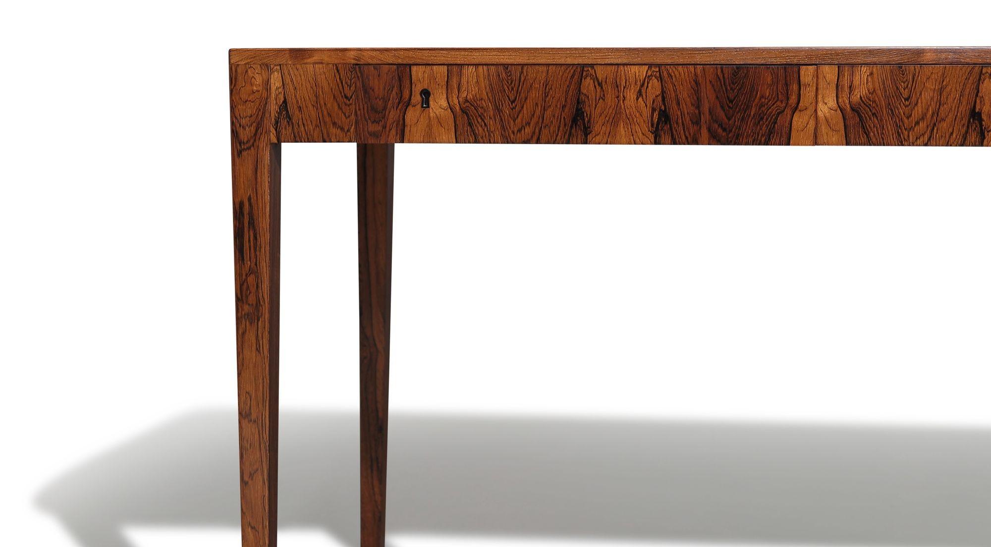 Elegant Mid-century Danish rosewood writing desk designed by Riis Antonsen, Denmark, 1955. Crafted from rosewood with book-matched grain, the desk features two small locking drawers and is raised on tapered legs.

Measurements
W 47.25'' x D 23.50''