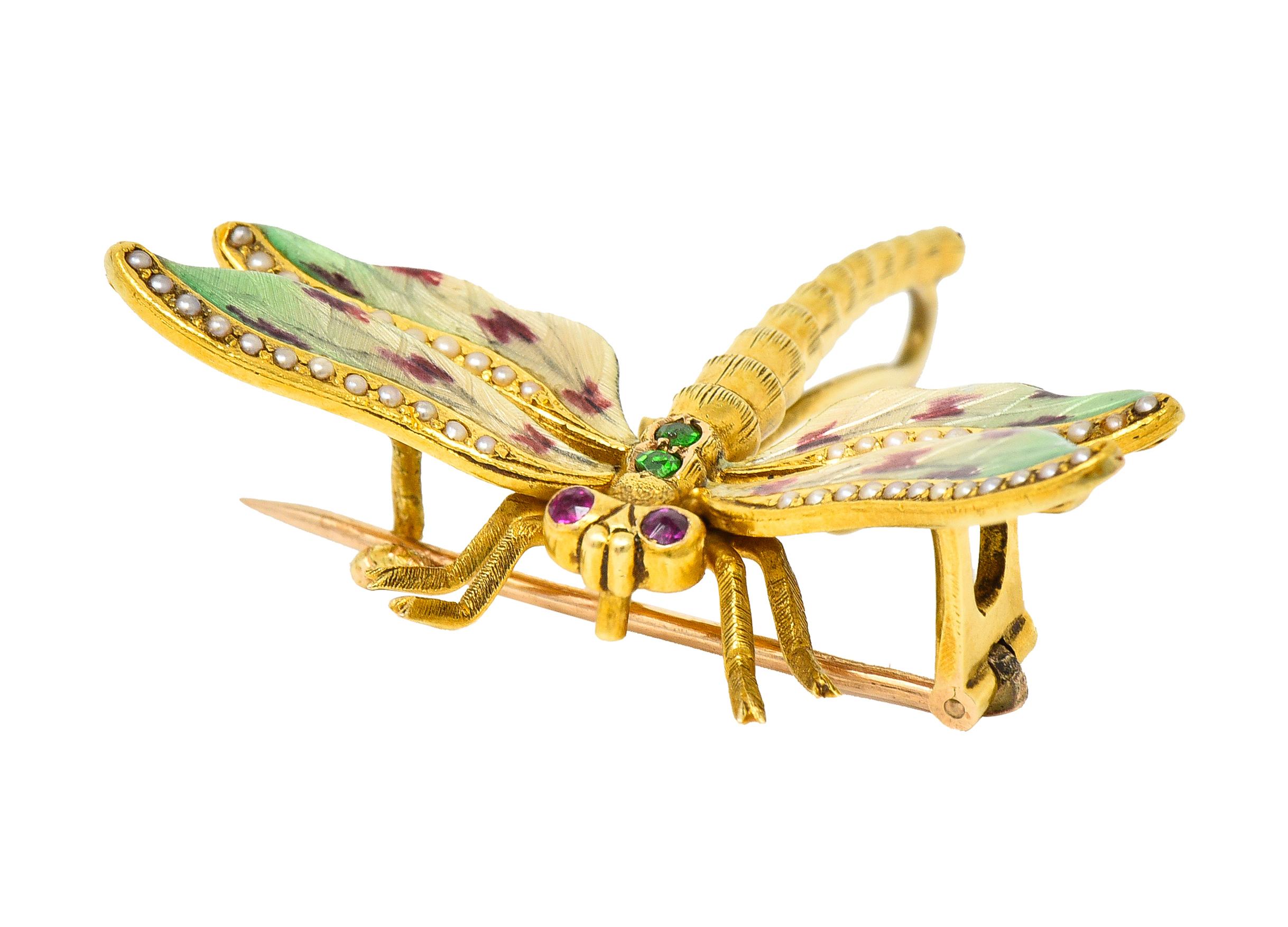 Designed a dragonfly with a segmented gold body and four basse-taille enamel wings. Transparent red, green, and yellow glossy enamel over linear vein-like engraving. Exhibiting minimal loss - accented by 1.0 mm round seed pearls. Bead set in edges