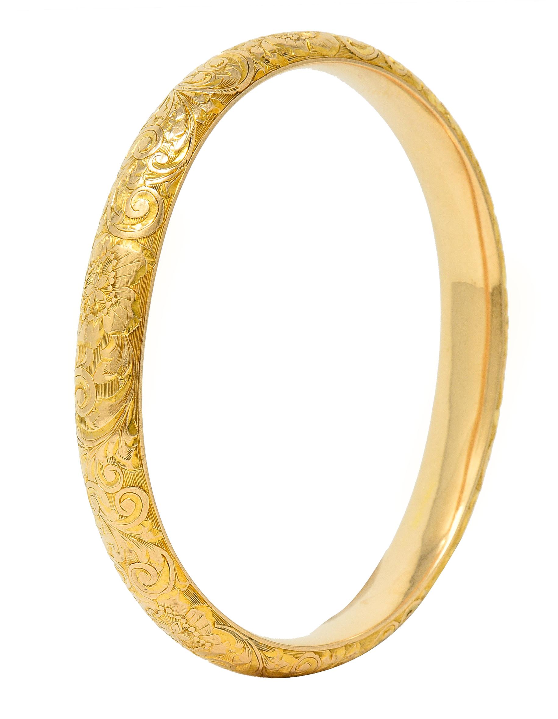Designed as a curved bangle with an engraved scroll motif fully around
Featuring orange blossom flowers engraved throughout 
With linear texture throughout 
Stamped for 14 karat gold 
With maker's mark for Riker Brothers
Circa: 1905
Width at widest:
