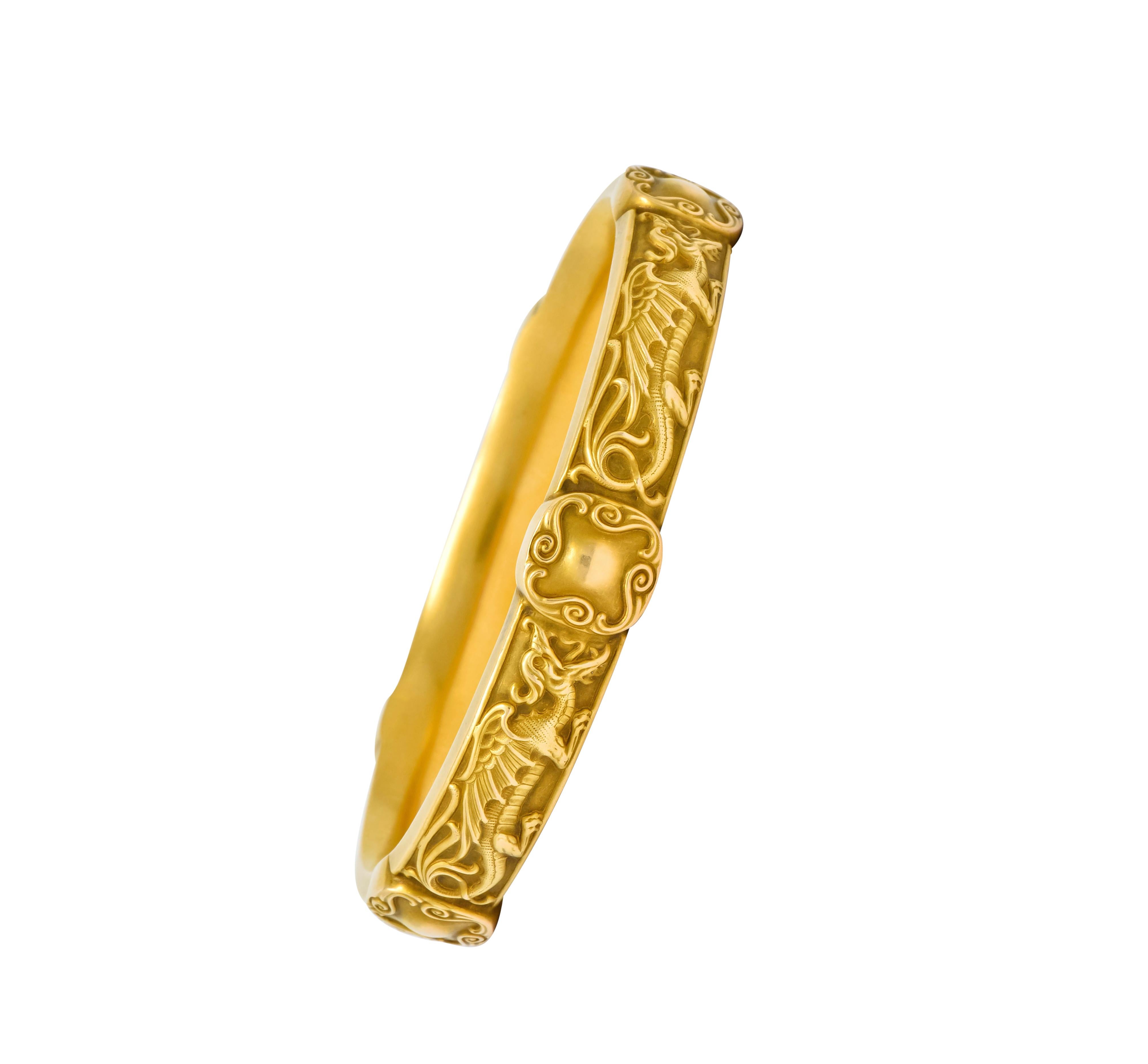 Designed as a bangle bracelet featuring stylized dragons in crouched and breathing fire

Accented throughout by five cushion shaped stations with scrolled surrounds

Maker's mark for Riker Brothers and stamped 14k for 14 karat gold

Circa