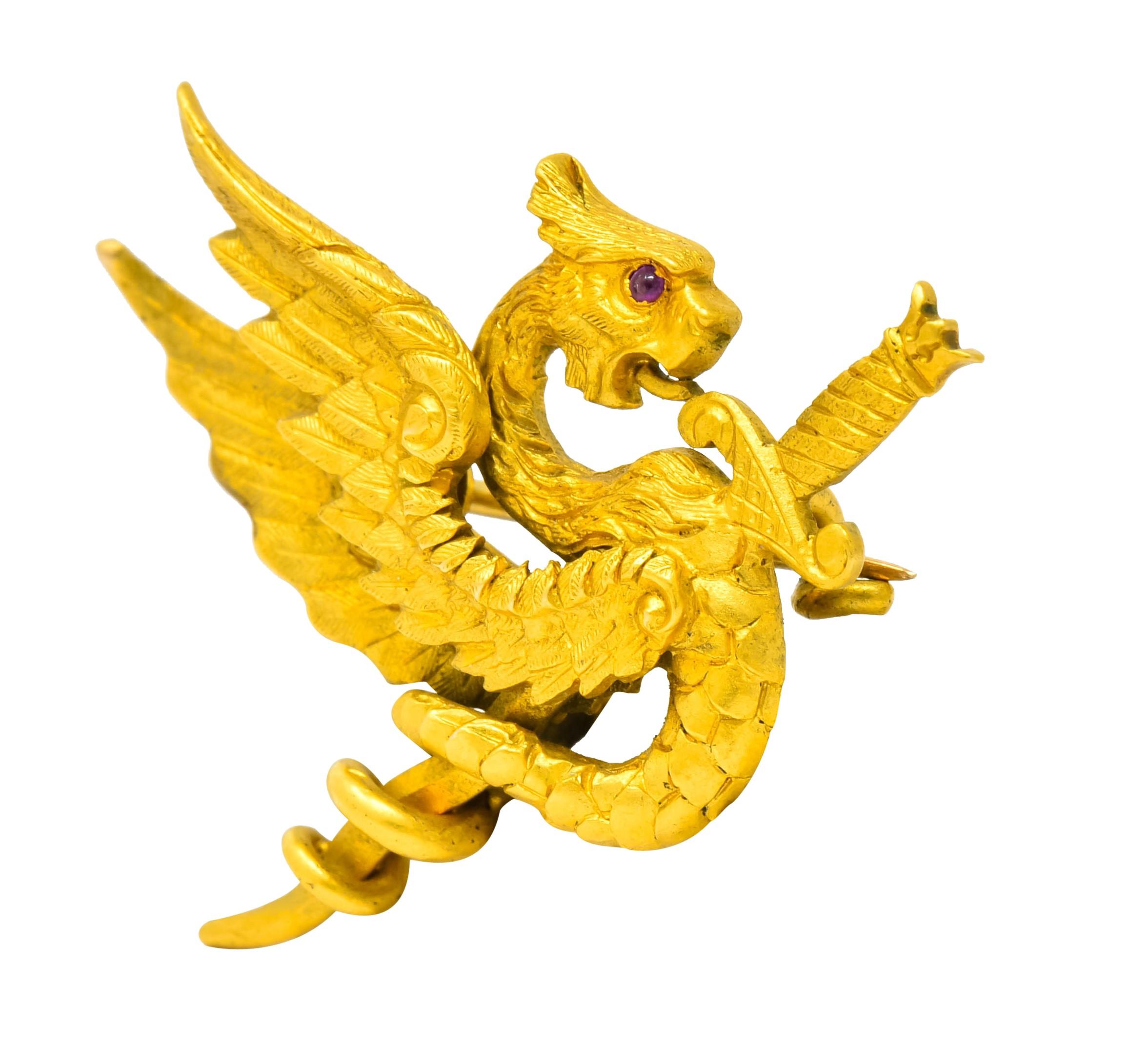 Brooch designed as a fierce winged dragon, highly rendered in matte gold with defined feathers, fur, and scales

With ruby eye accent, a sword thrust through its chest and its serpent tail coiled around the blade

Completed by pin stem and