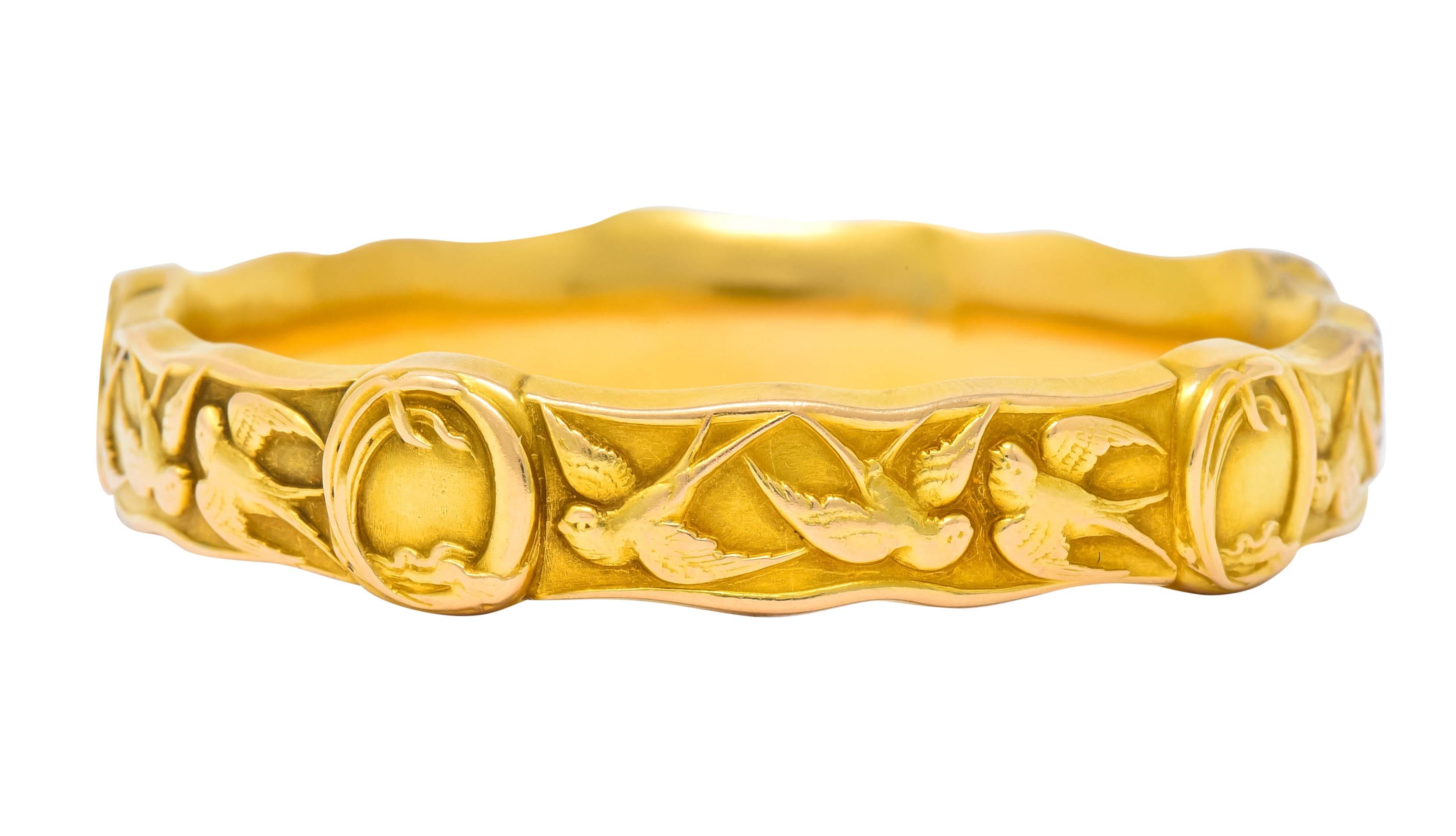 Designed as a wavy edged bangle bracelet decorated throughout by swallow motif in three different patterns of flight

Accented by five oval stations with raised stylized ribbon borders

With maker’s mark for Riker Brothers and stamped 14k for 14