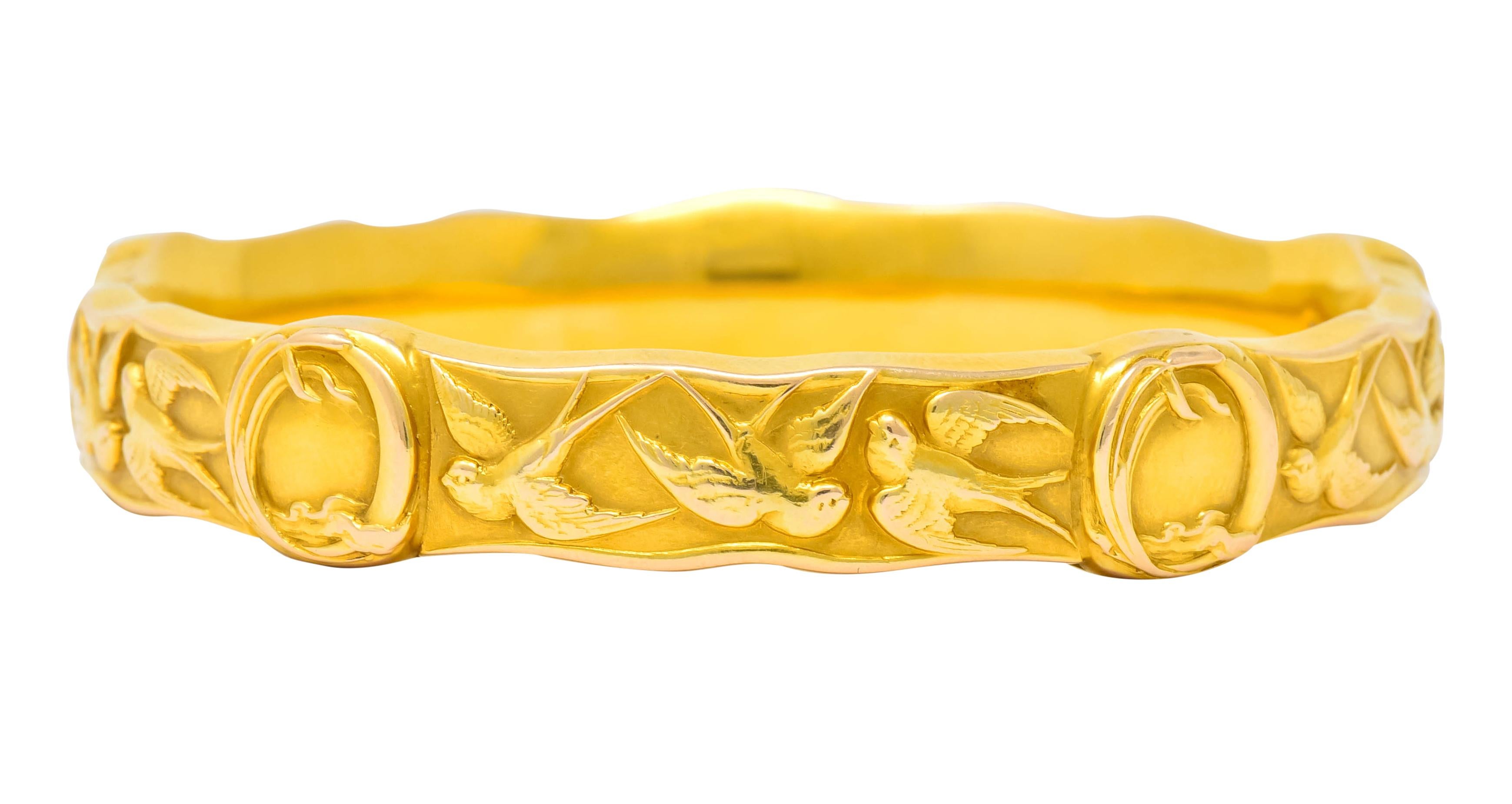Designed as a wavy edged bangle decorated by highly rendered swallows, mid-flight

Accented by five oval stations framed by whiplash surrounds

Maker’s mark for Riker Brothers and stamped 14k for 14 karat gold

Circa 1900 with dated