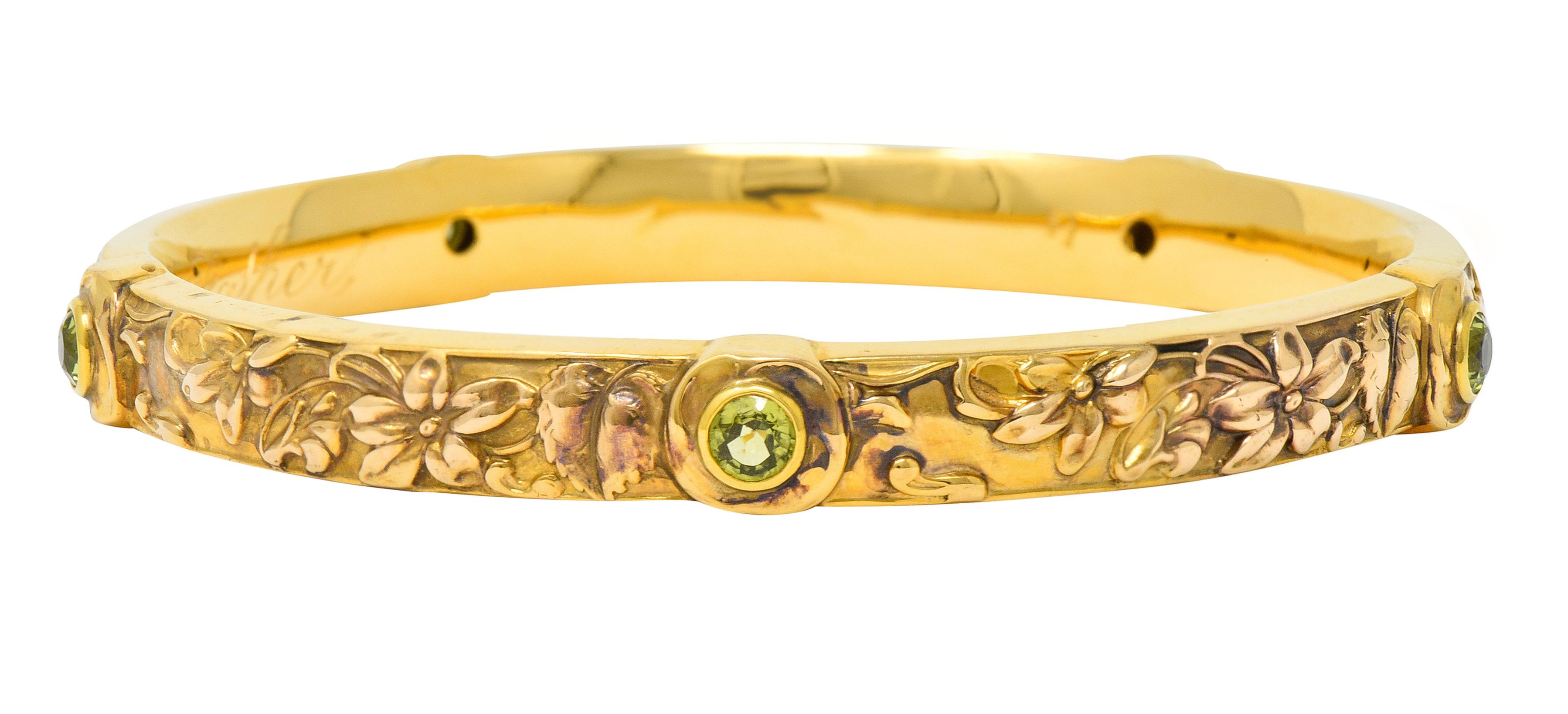 Bangle style bracelet features highly rendered repoussè floral imagery

With five gemstone stations bezel set with round cut peridot weighing in total approximately 1.90 carats

Very well-matched and bright yellowish-green in color

With loving