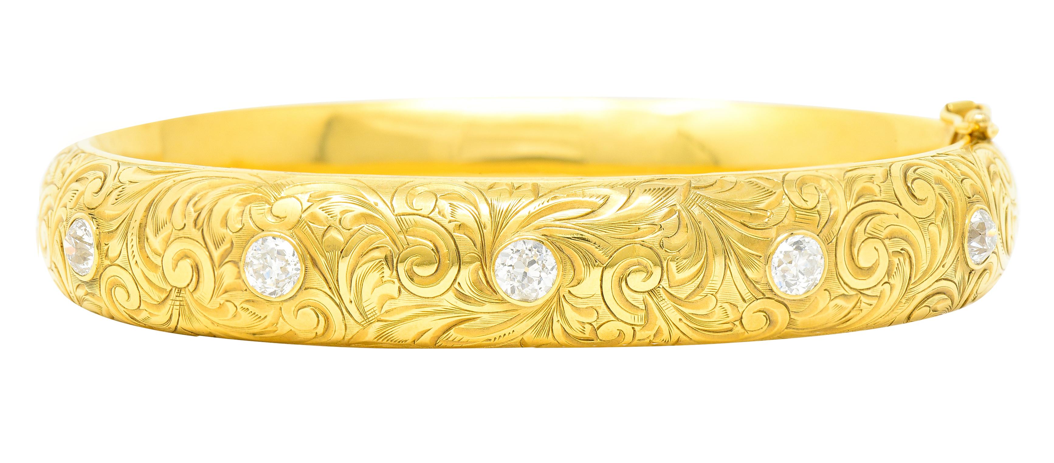 Hinged bangle bracelet is deeply engraved fully around by flourishing foliate. And bezel set to front by five old mine cut diamonds. Weighing collectively approximately 1.45 carats - G/H color with SI1 to VS2 clarity. Completed by a figure eight