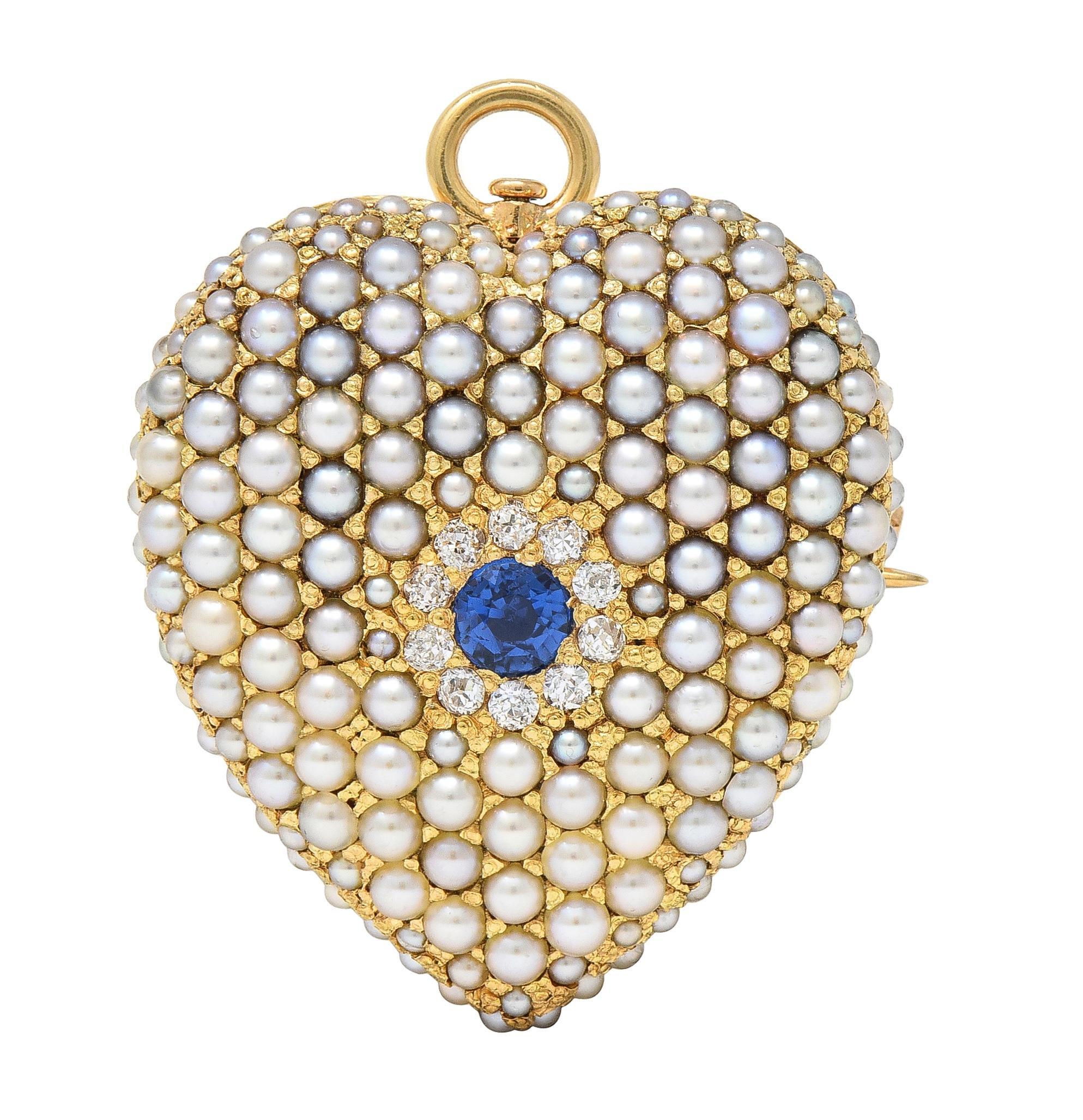 Designed as a puffed heart form centering a round cut sapphire weighing approximately 0.20 carat
Transparent medium blue in color with a halo surround of old European cut diamonds 
Weighing approximately 0.20 carat total - eye clean and bright 
Bead