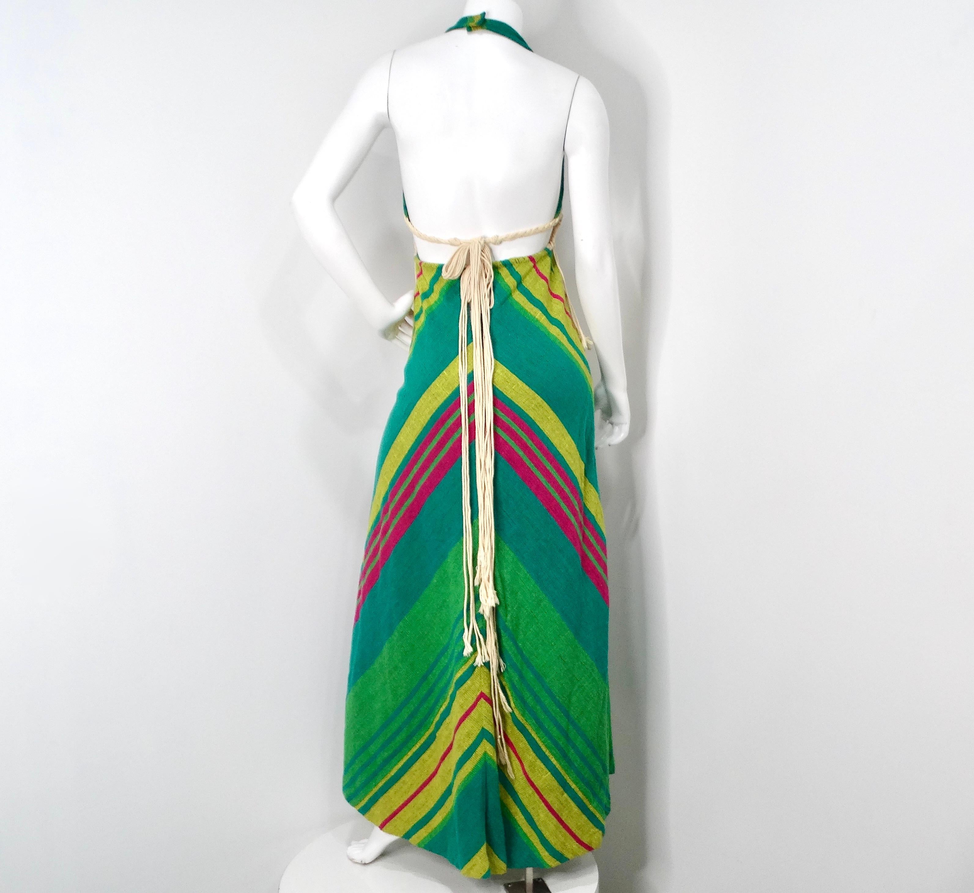 Il Rikma 1970s Green Multicolor Macrame Handmade Cotton Halter Maxi Dress è un capolavoro bohémien che incarna l'essenza libera degli anni Settanta. Questo splendido maxi abito vanta un vivace sfondo verde ornato da una sorprendente stampa a strisce
