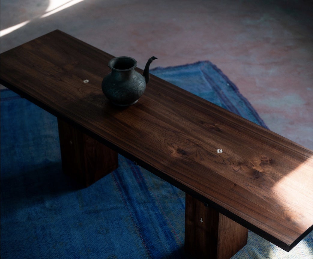 Les motifs de la table basse Rikt s'inspirent de ceux que l'on trouve dans les environs d'Udaipur.  Les motifs de fleurs et de croix sont façonnés à la main dans le chêne, puis incrustés dans une cavité sculptée dans la table en teck, contrastant