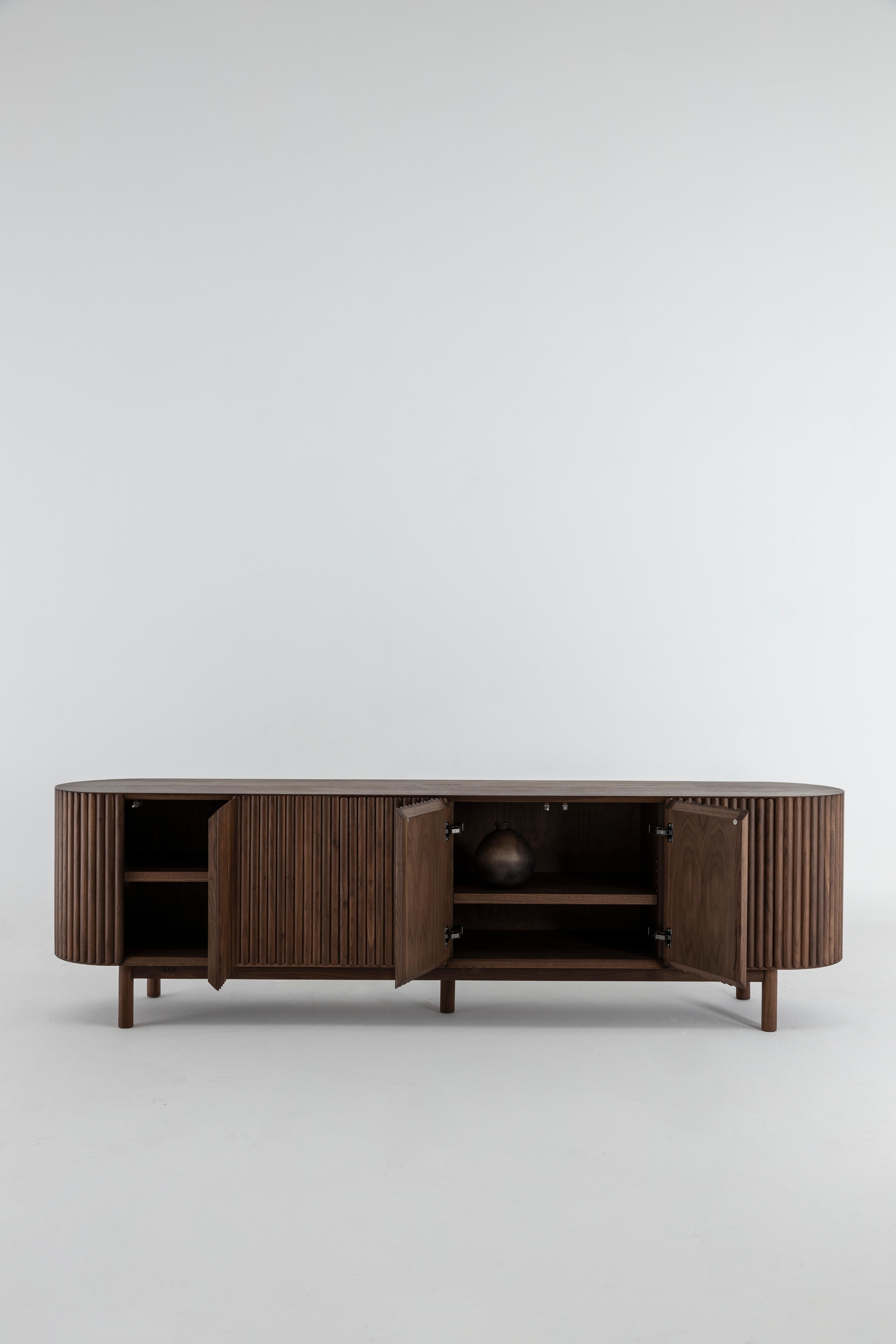 Between the sculpture and the functionality of the object, the RIMA credenza is inspired by the dynamism and the cadence of a poem, drawing all the attention to the wooden slats that are repeated one after the other to form a texture that embraces